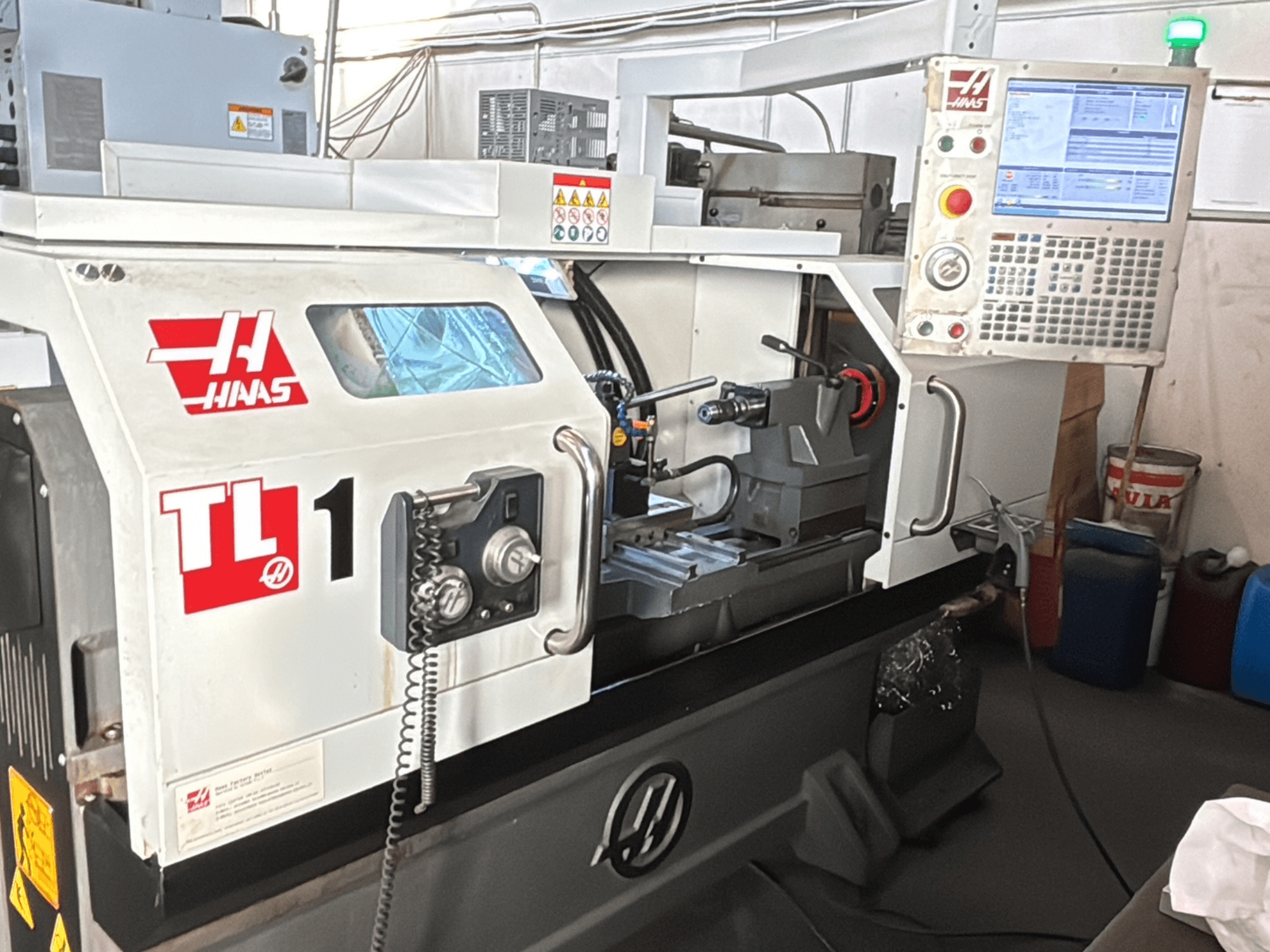 Haas TL-1 CNC tokarski stroj, prednji pogled, ima upravljačku ploču sa zaslonom, držač alata i sigurnosne naljepnice.