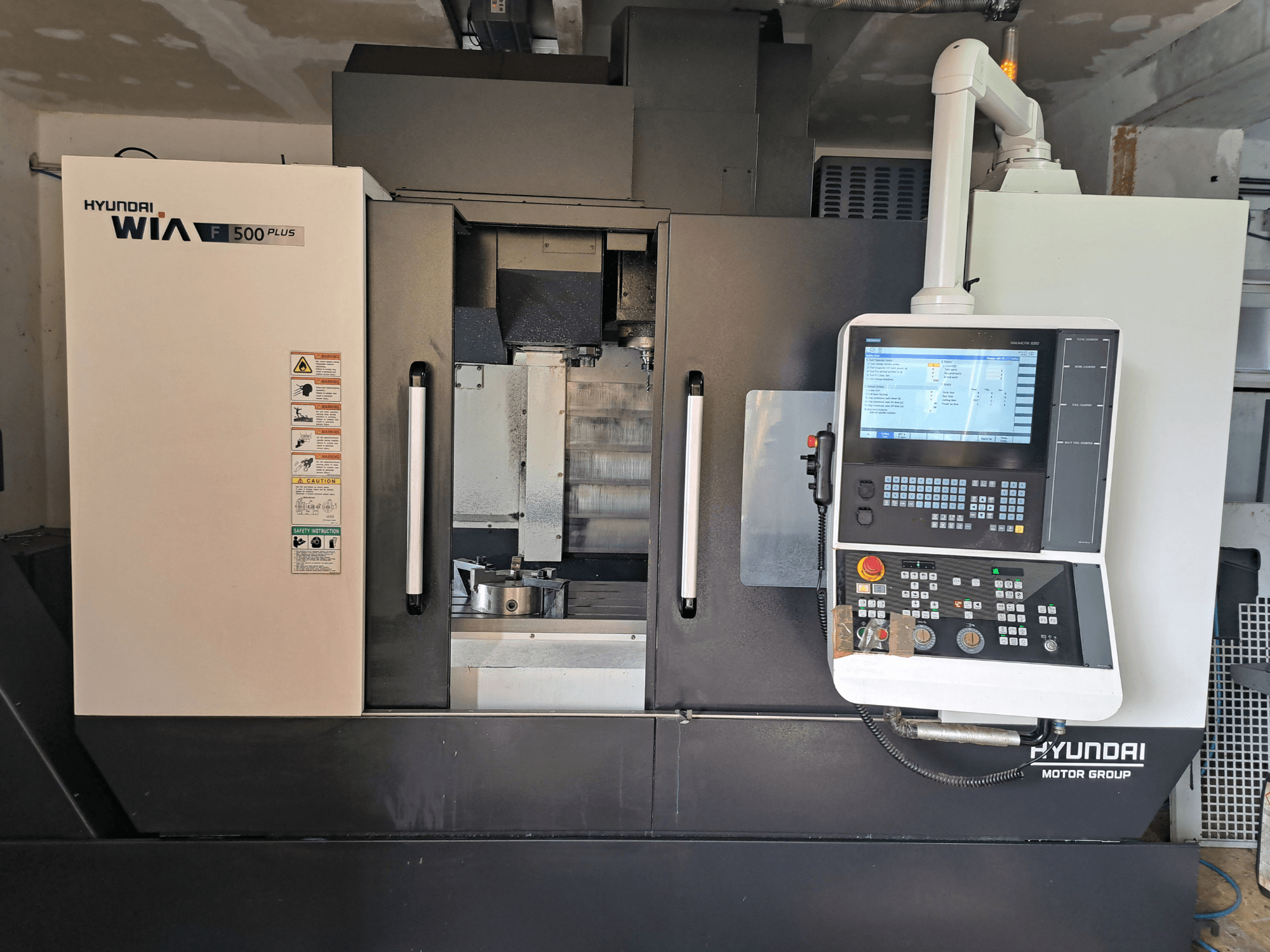 CNC stroj Hyundai WIA F500 Plus u prednjem pogledu, s digitalnom upravljačkom pločom i sigurnosnim naljepnicama.