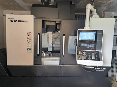 CNC stroj Hyundai WIA F500 Plus u prednjem pogledu, s digitalnom upravljačkom pločom i sigurnosnim naljepnicama.
