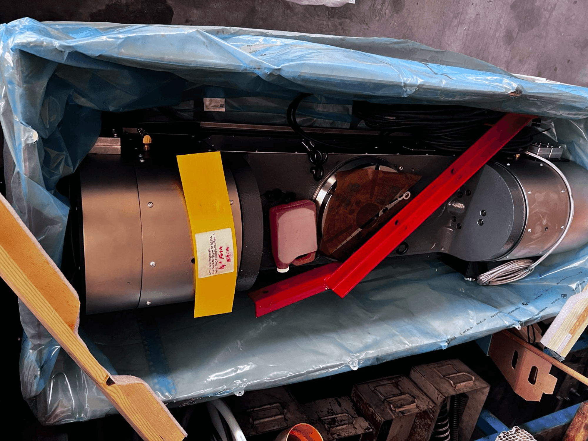 Motorni uređaj djelomično vidljiv u pakiranju, ima srebrnu vanjštinu, šarene mjerače i crvenu potpornu šipku.