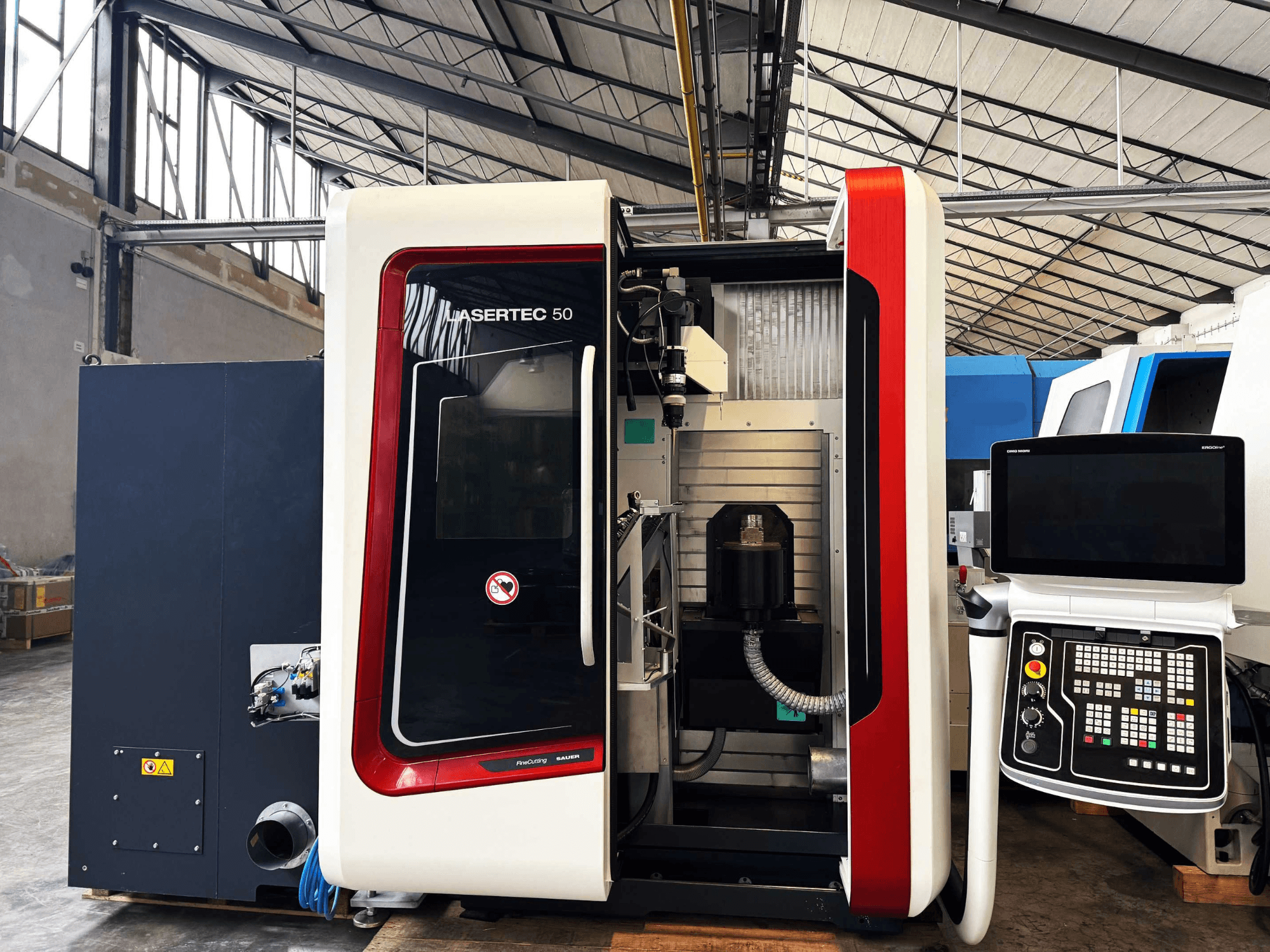 Bočni prikaz CNC stroja LaserTec 50 s crno-bijelom upravljačkom pločom, vidljivim držačem alata i industrijskim okruženjem.
