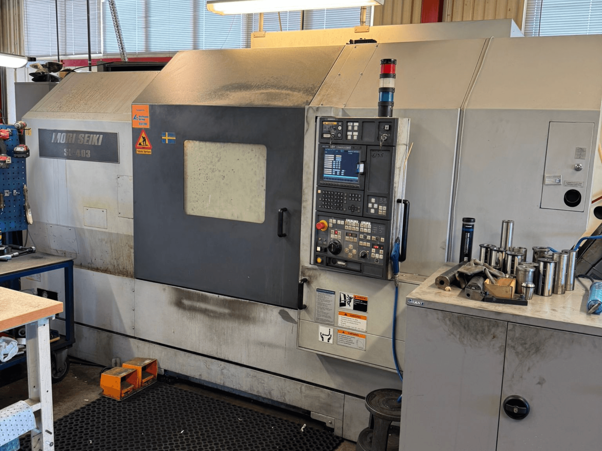 Horizontalni tokarski stroj MORI SEIKI SL-403BMC/800 u radionici, s prikazom upravljačke ploče i obližnjih alata, bočni pogled.