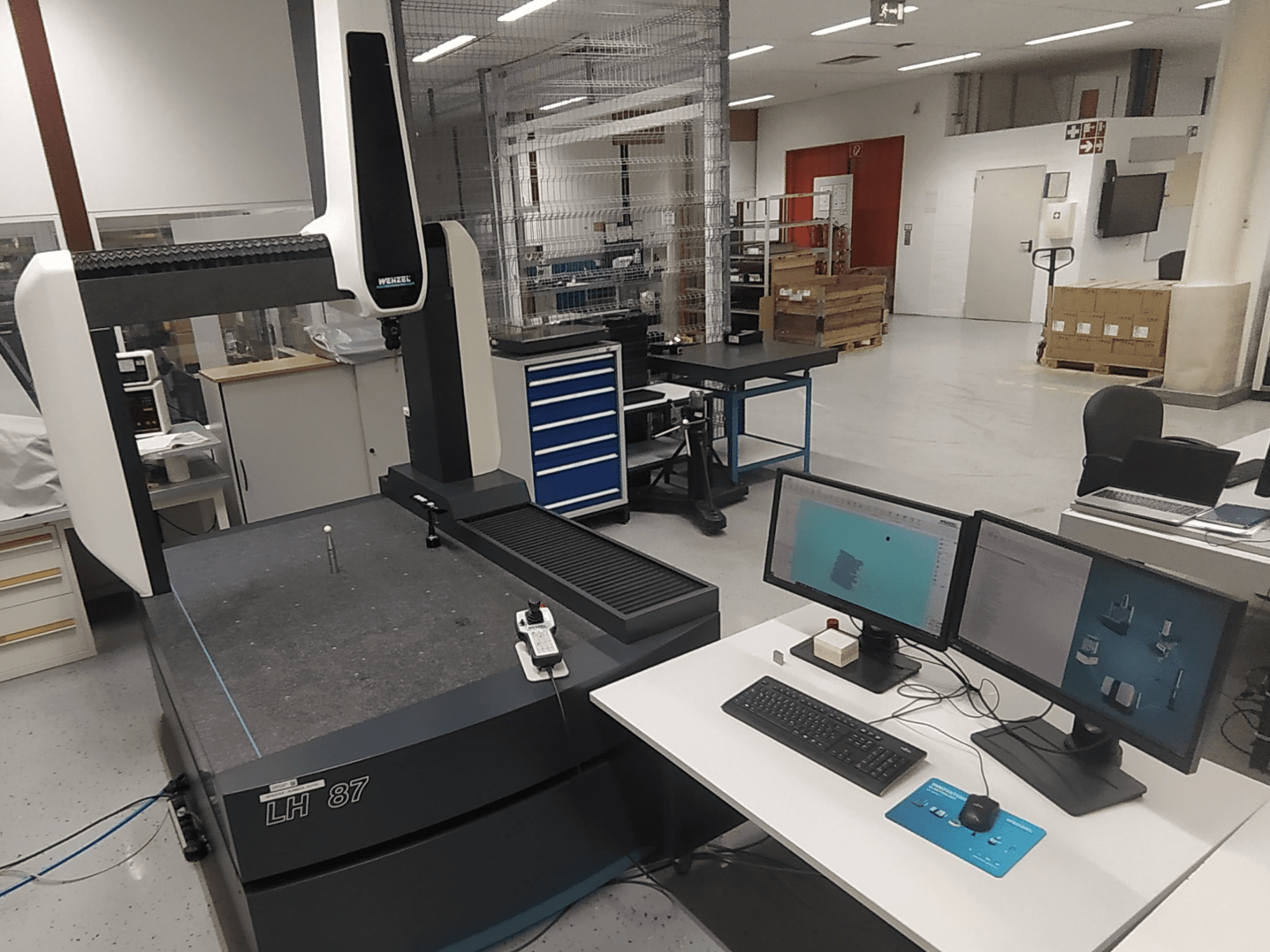 Koordinatni mjerni stroj Wenzel LH 87 vidljiv u laboratorijskom okruženju, s dva monitora i mjernom sondom na stolu.