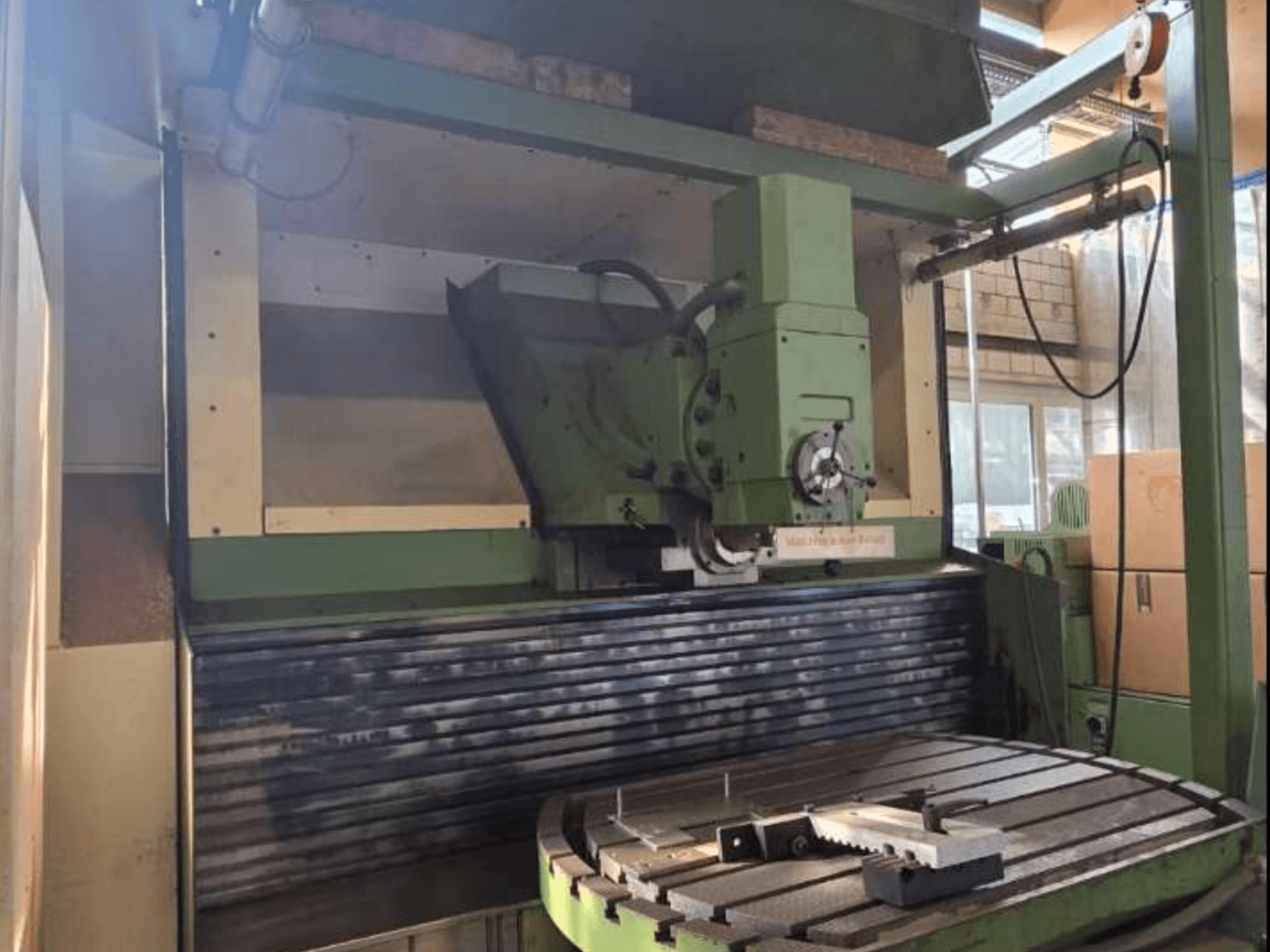 Univerzalni obradni centar MAHO MH1000 C u prednjem pogledu, prikazuje zelenu strukturu, vreteno i rotacijski stol s obratkom.