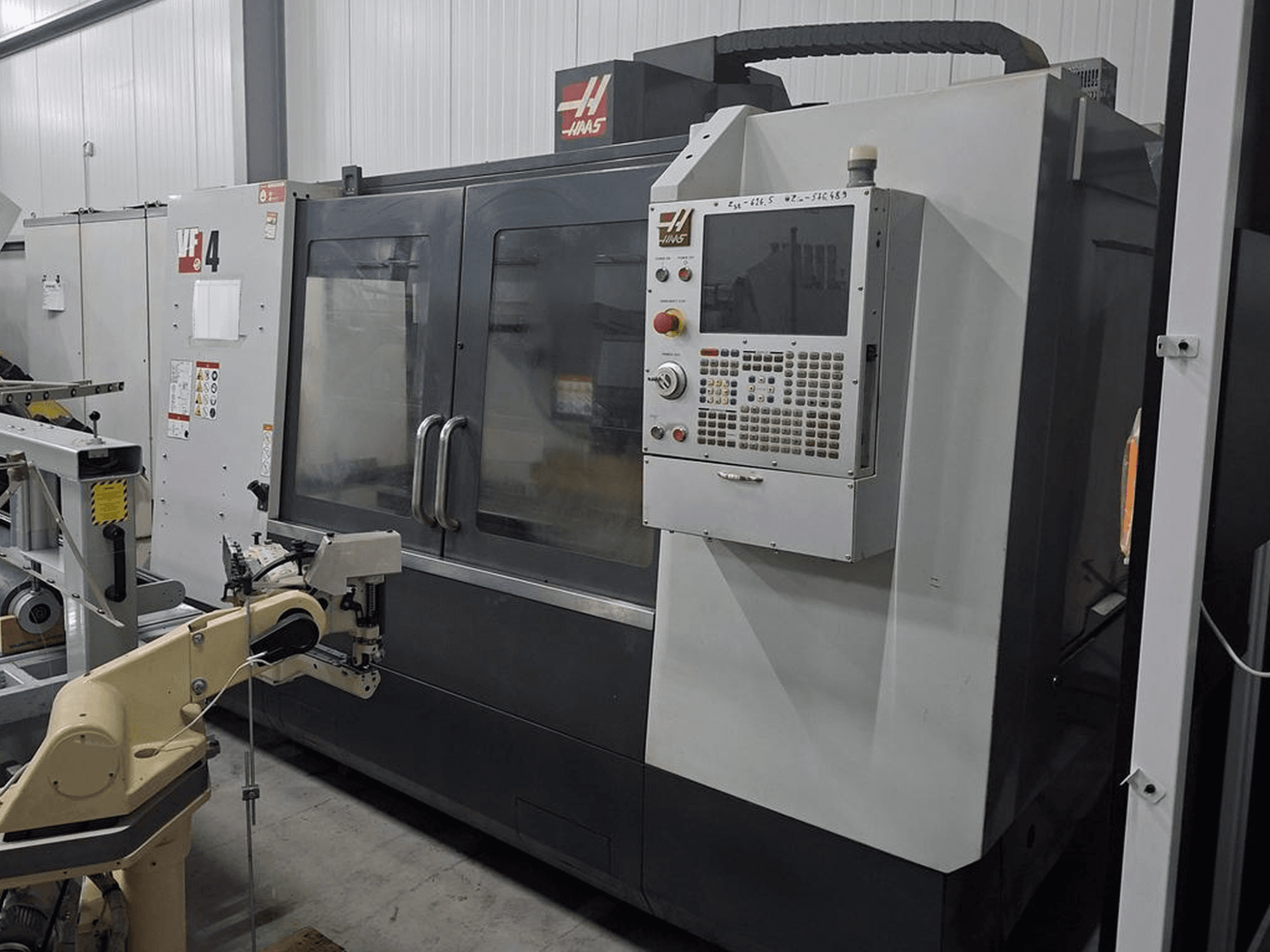 Haas VF-4 CNC glodalica s prednje strane, s numeričkom upravljačkom pločom i robotskom rukom za automatizaciju.