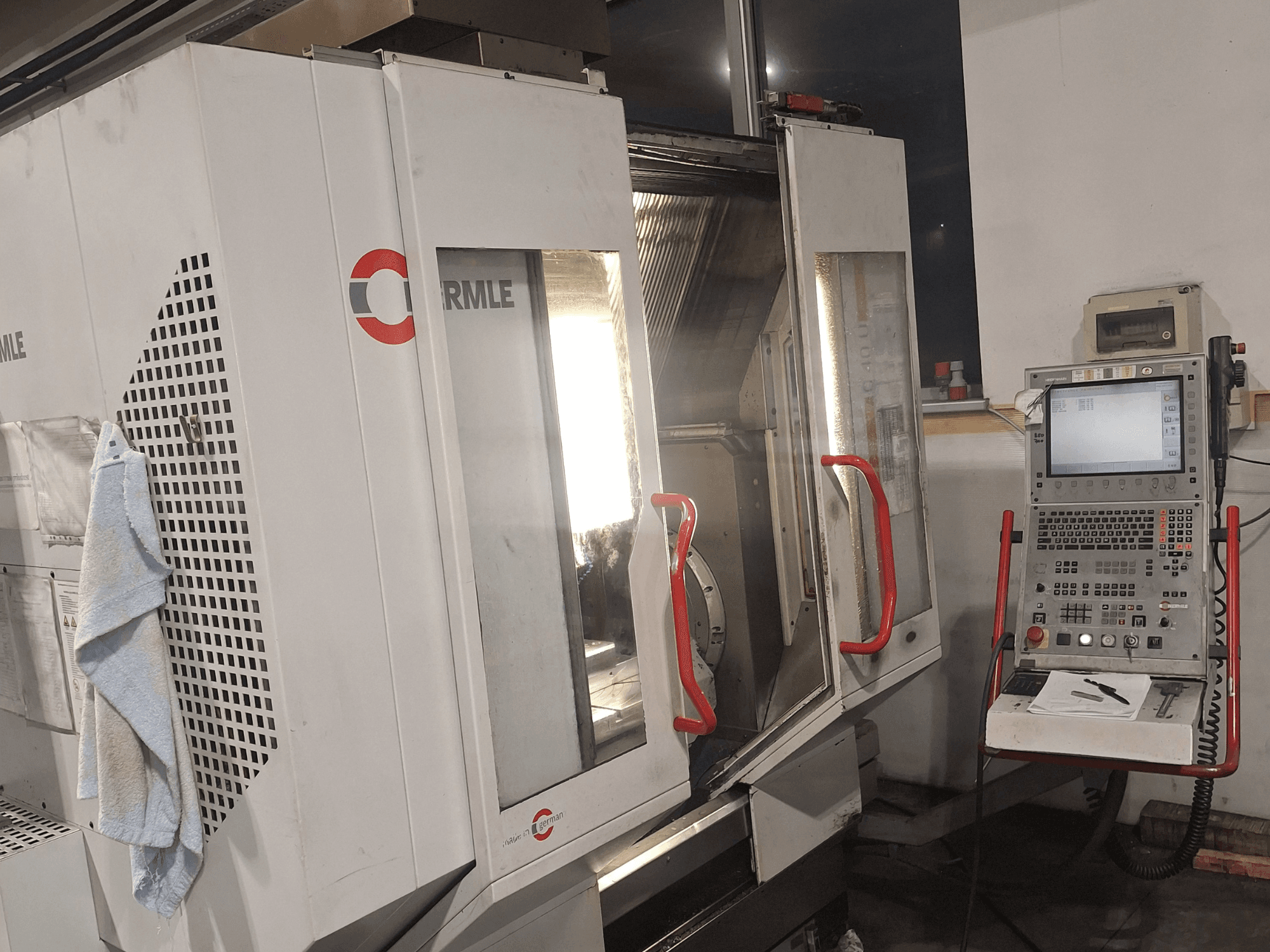 CNC stroj marke Cormile, prednji pogled s djelomično otvorenim vratima i upravljačkom pločom s ekranom i gumbima.