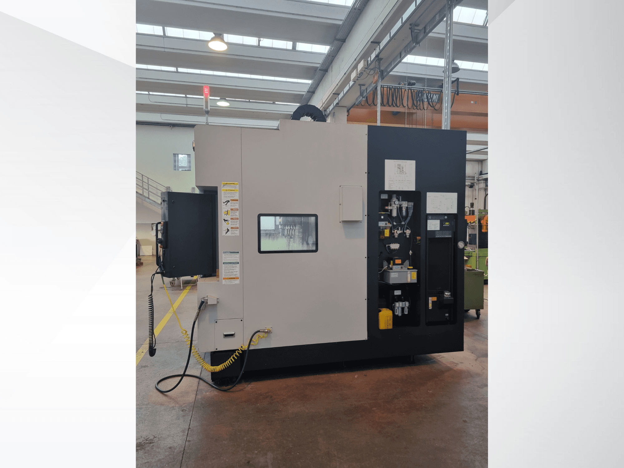 Industrijski stroj s bočne strane, ima upravljačku ploču s gumbima, indikatorima i sigurnosnom naljepnicom s upozorenjem.