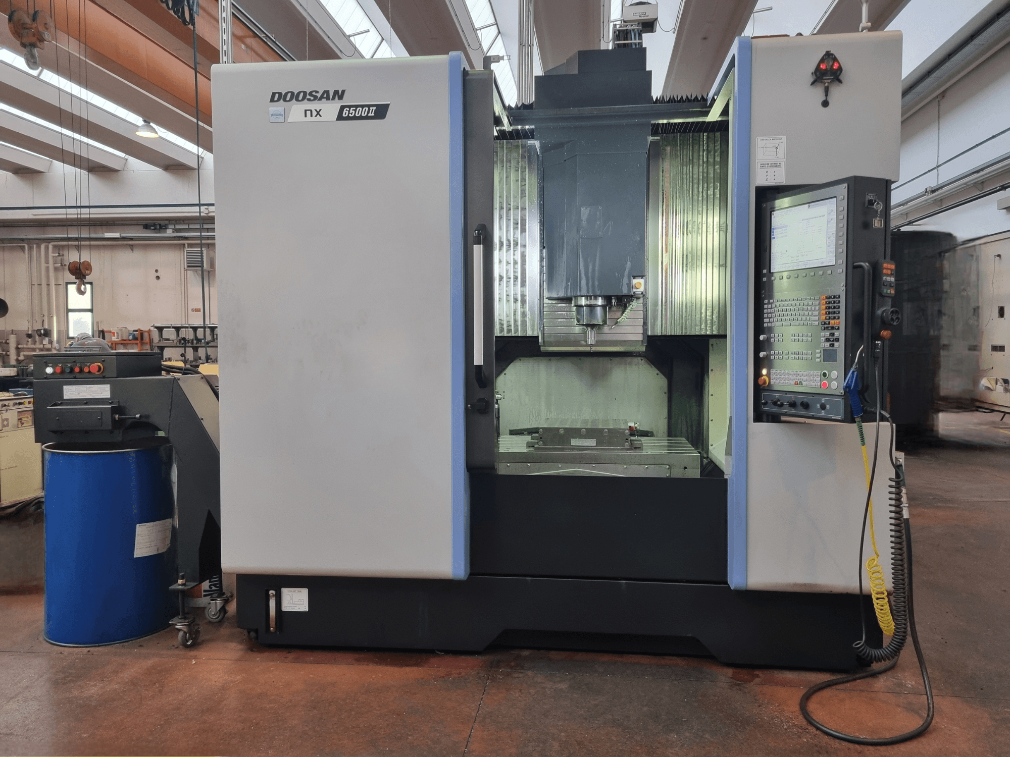 Doosan NX 6500 II CNC stroj, prednji pogled, s upravljačkom pločom i područjem za obradu, smještenim pored plavog cilindra.