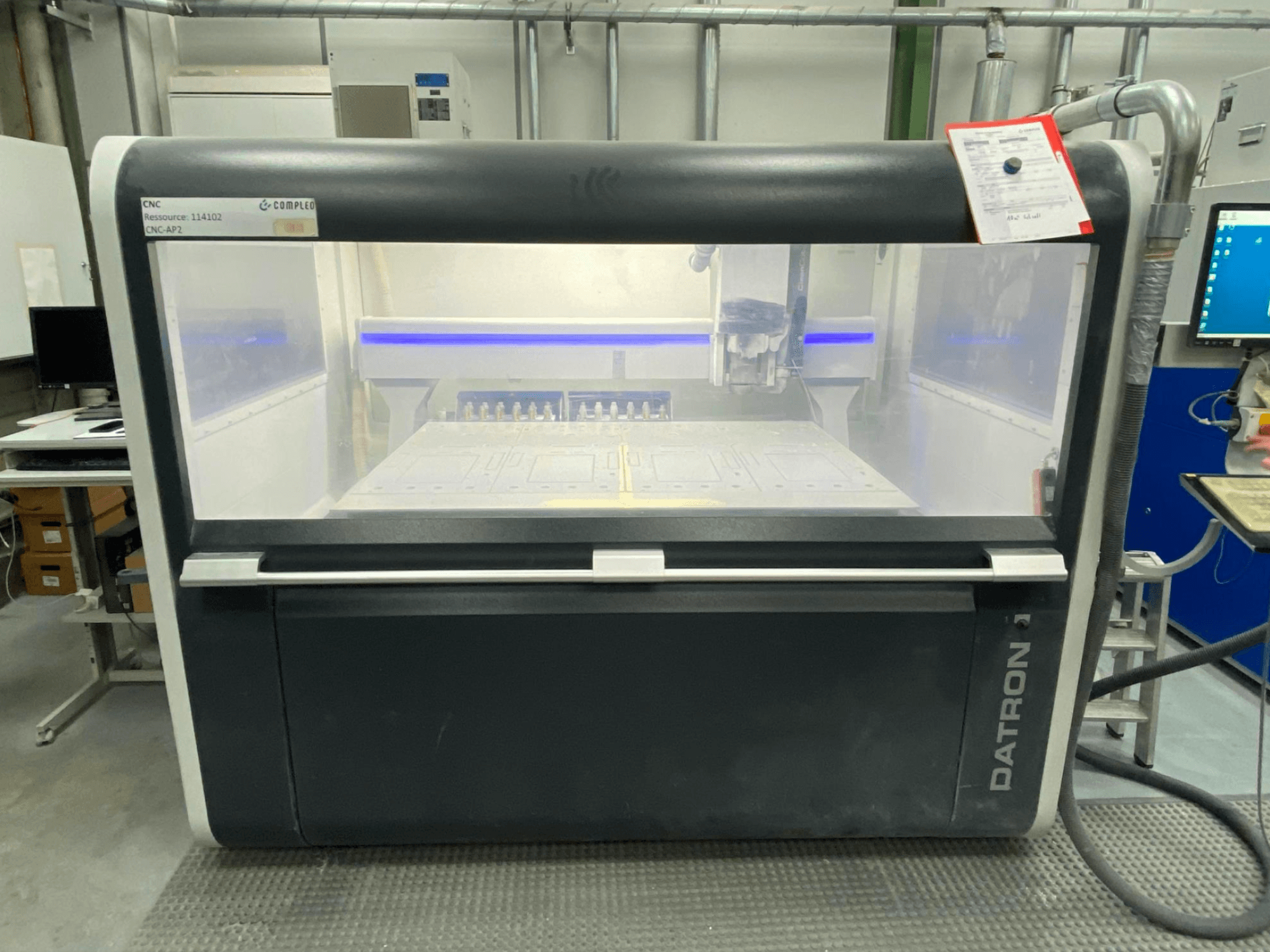 Prednji pogled na vertikalni obradni centar Datron MLCube B, s vidljivim kontrolama i radnim stolom, u radioničkom okruženju.