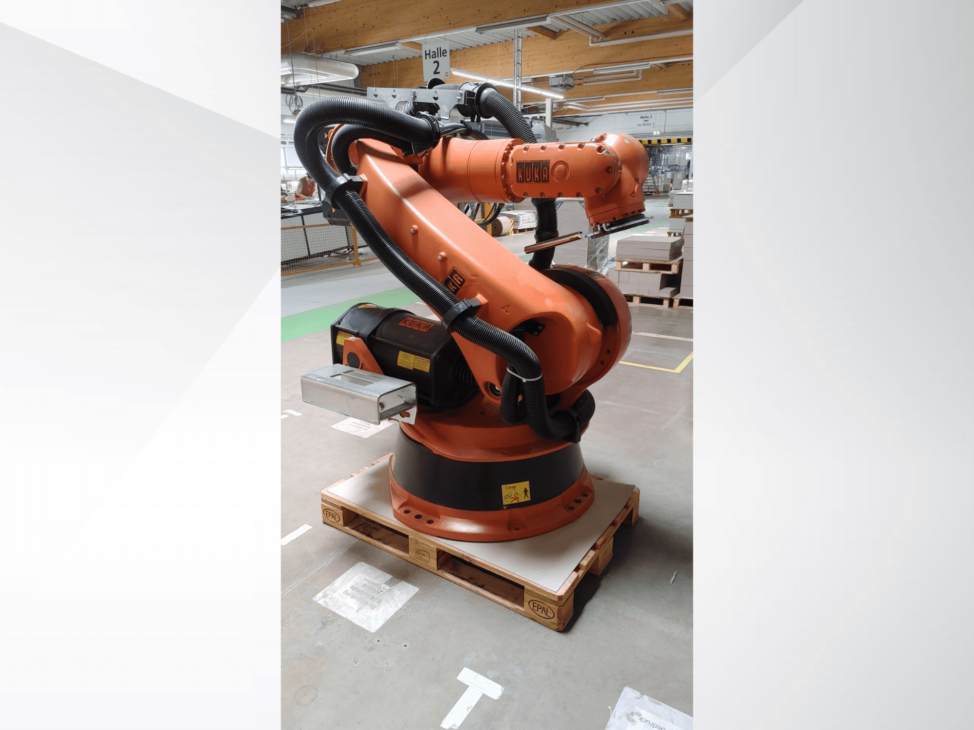 KUKA KR140-3 COMP robotska ruka u narančastoj boji, prednji pogled na drvenoj paleti, sa zakrivljenom rukom i upravljačkom kutijom.