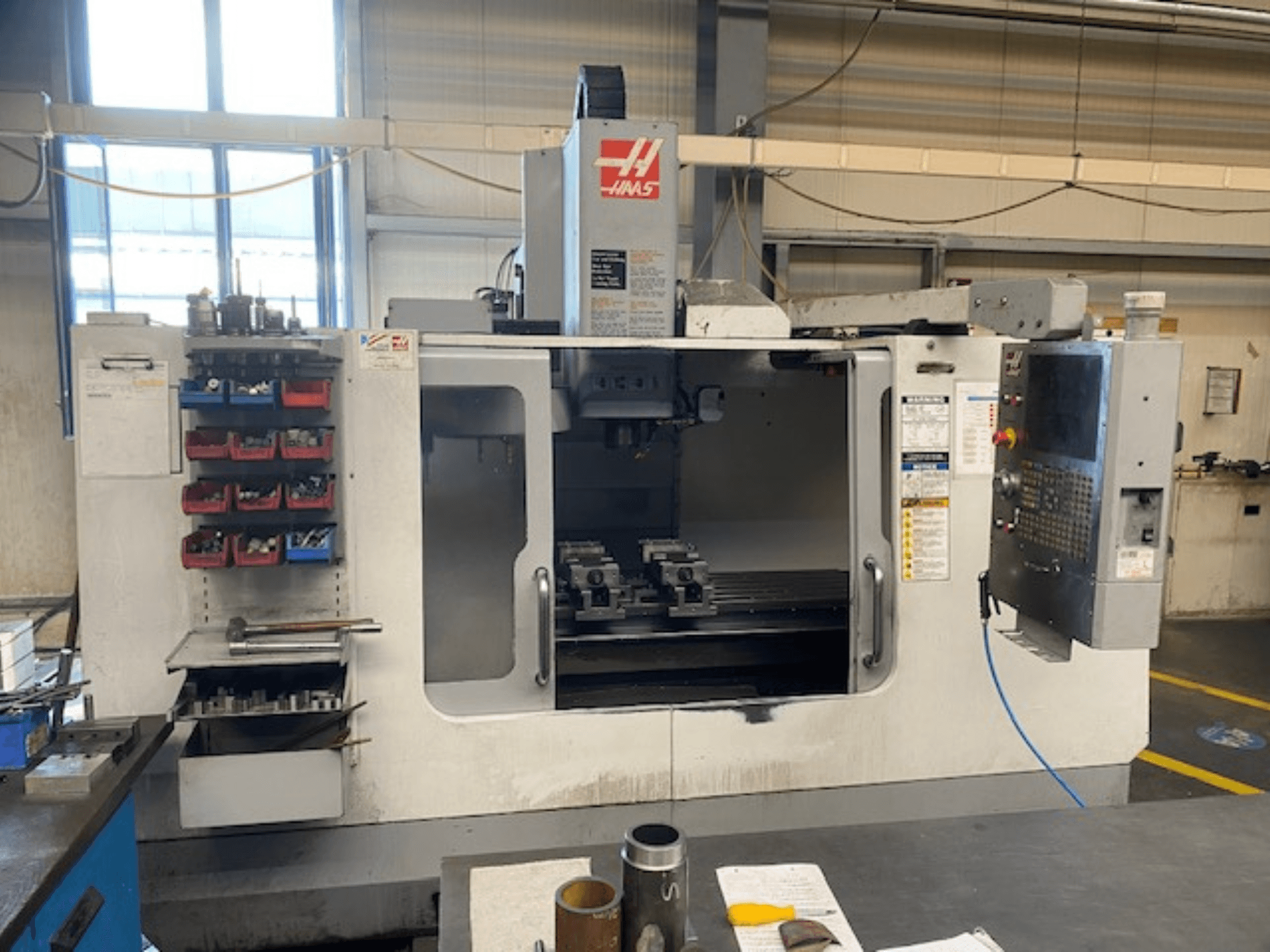 Prednji pogled na Haas CNC glodalicu, model VF-2, s vidljivim alatima za pohranu alata, upravljačkom pločom i radnim prostorom.