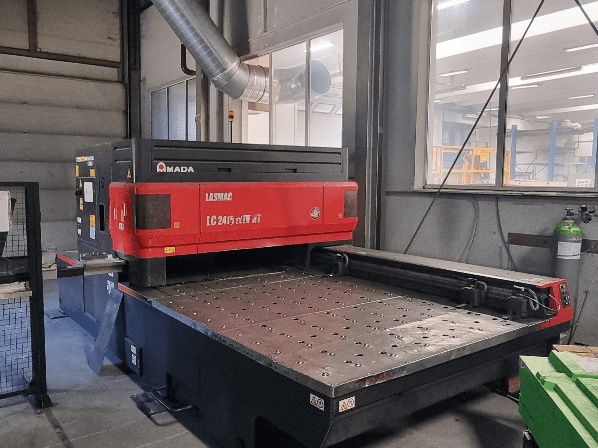 Amada LASMAC LC 2415 αⅡ NT laserski rezač u crvenoj i crnoj boji, prednji pogled, s motoriziranom rezačkom platformom i preciznim kontrolama.