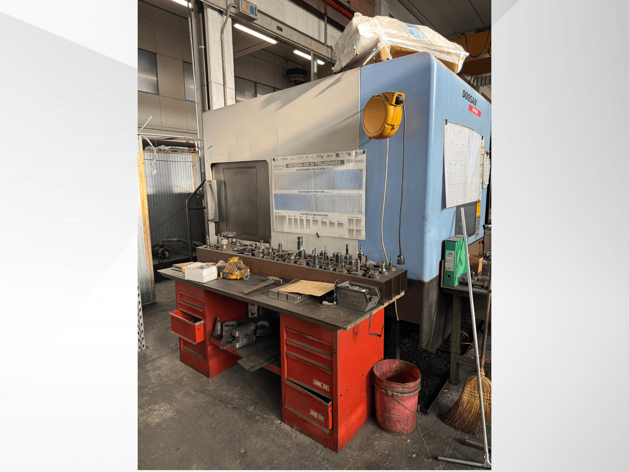 Doosanov obradni centar s crvenim radnim stolom i prostorom za pohranu, na kojem su izloženi alati i oprema, gledano sprijeda.