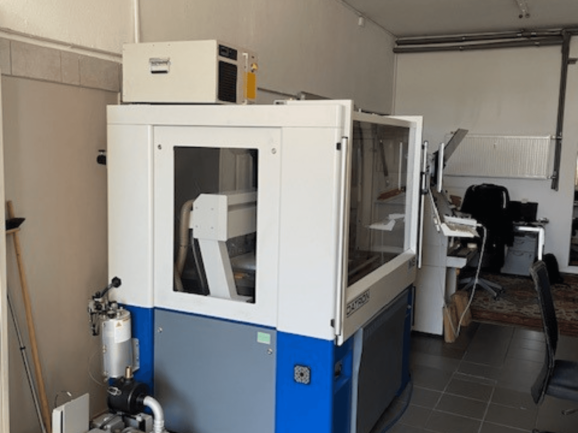 Plavo-bijeli industrijski stroj s prozirnim pločama, prednji pogled, uključuje upravljački pristup i vidljivu ventilacijsku jedinicu.