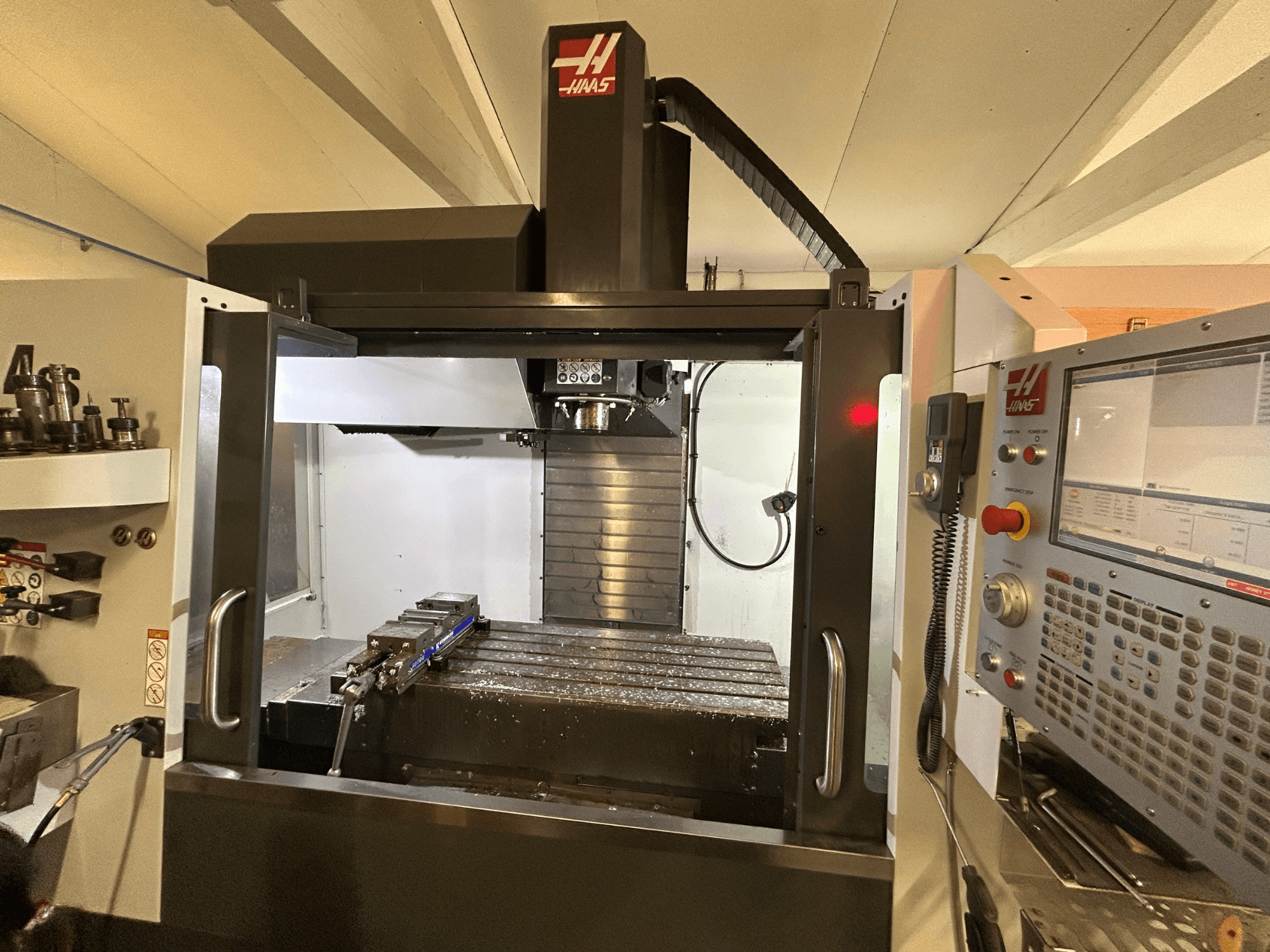 Vertikalni obradni centar HAAS VF-4SS, prednji pogled, prikazuje upravljačku ploču, držač alata i radno područje s metalnim strugotinama.