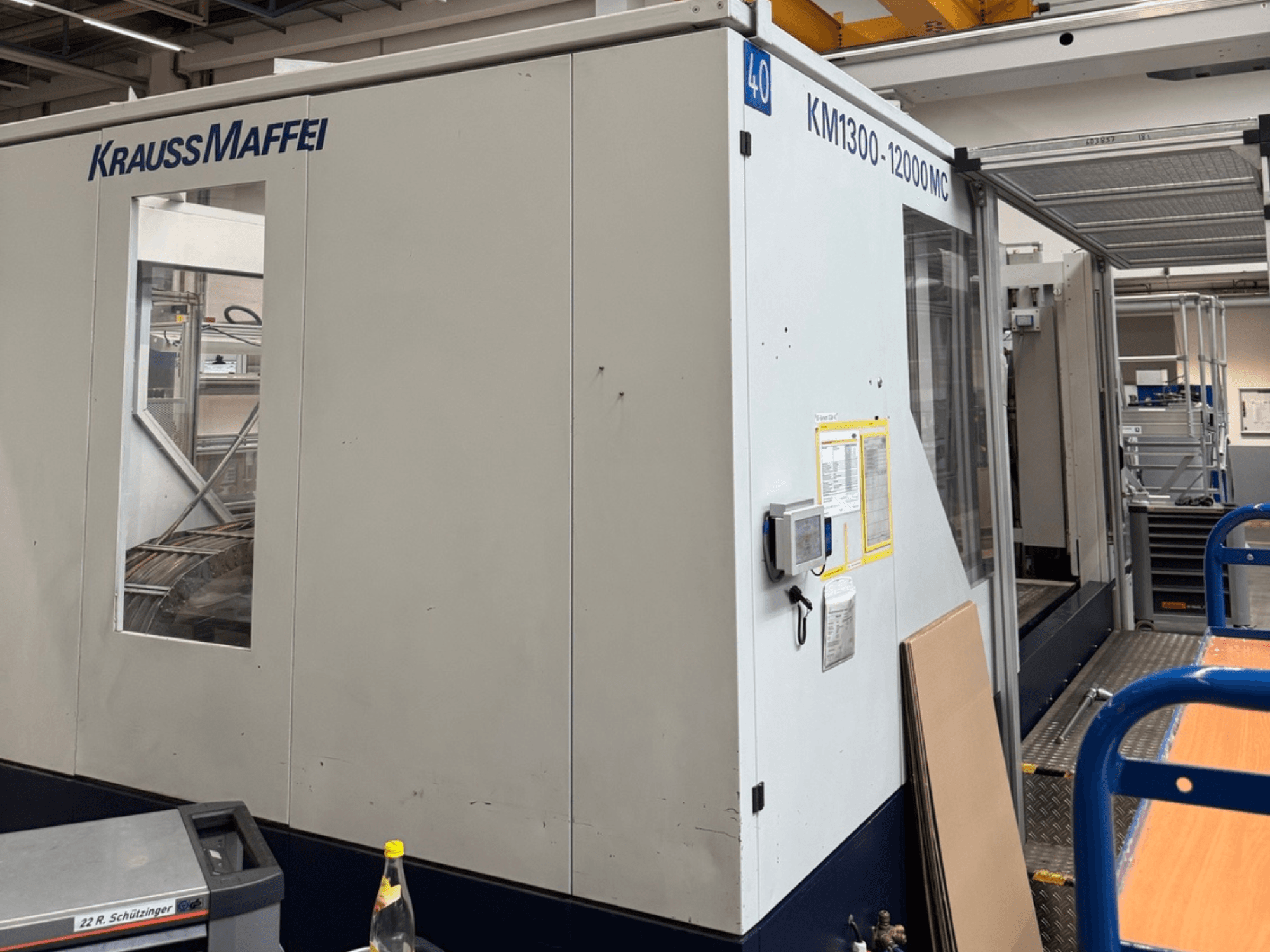 Krauss Maffei hidraulički stroj za brizganje plastike KM1300-12000 MC, bočni pogled, s prikazom upravljačke ploče i radnog prostora.