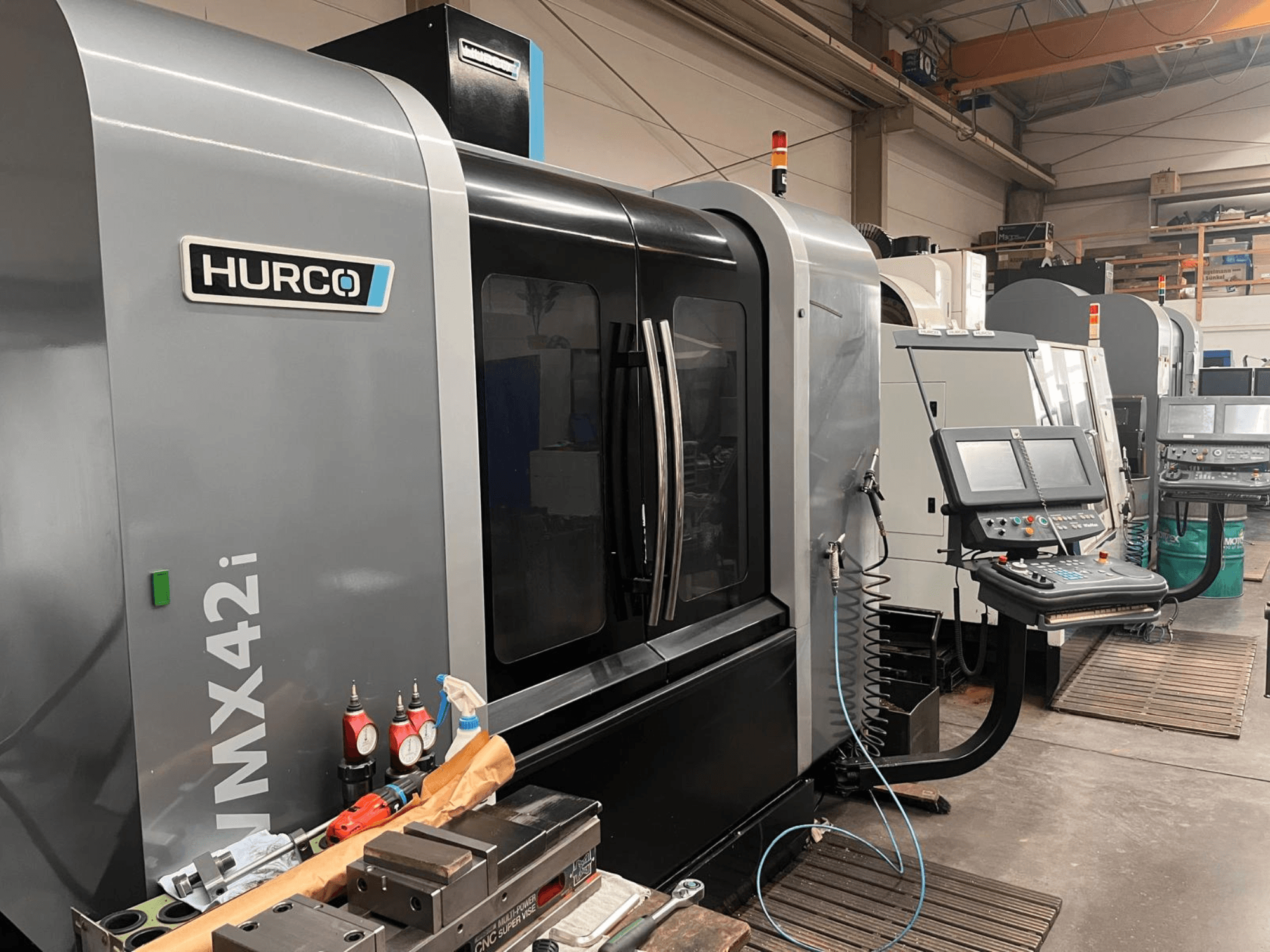 Hurco VMX42i CNC stroj u radionici, prednji pogled, s upravljačkom pločom i raznim alatima na radnom stolu.