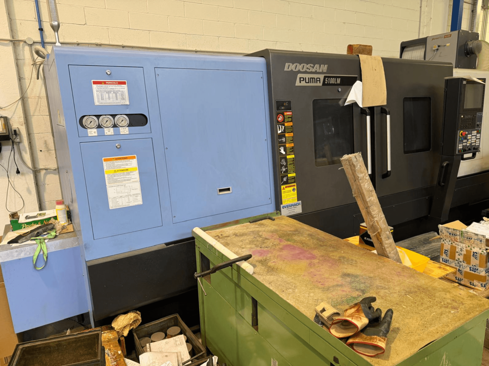 Doosan Puma 5100LM CNC stroj i upravljačka ploča, bočni pogled. Mjerači i naljepnice s upozorenjima vidljivi su na plavoj upravljačkoj jedinici.