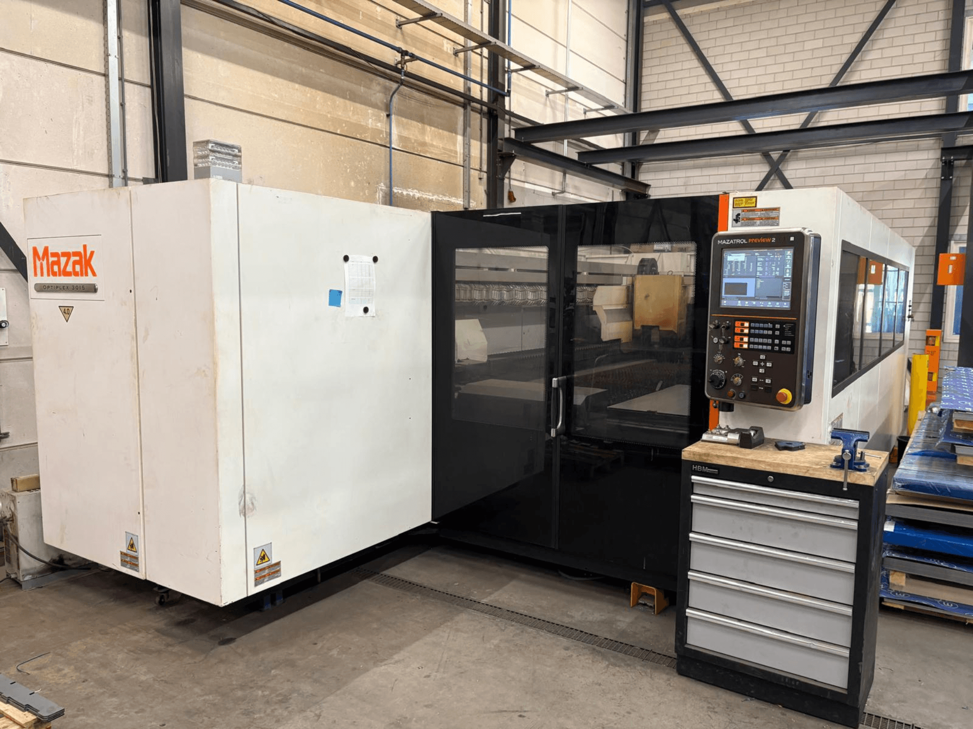 Mazak Optiplex 3015 CO2 stroj za lasersko rezanje, pogled sprijeda, s prikazom upravljačke ploče i industrijskog okruženja.