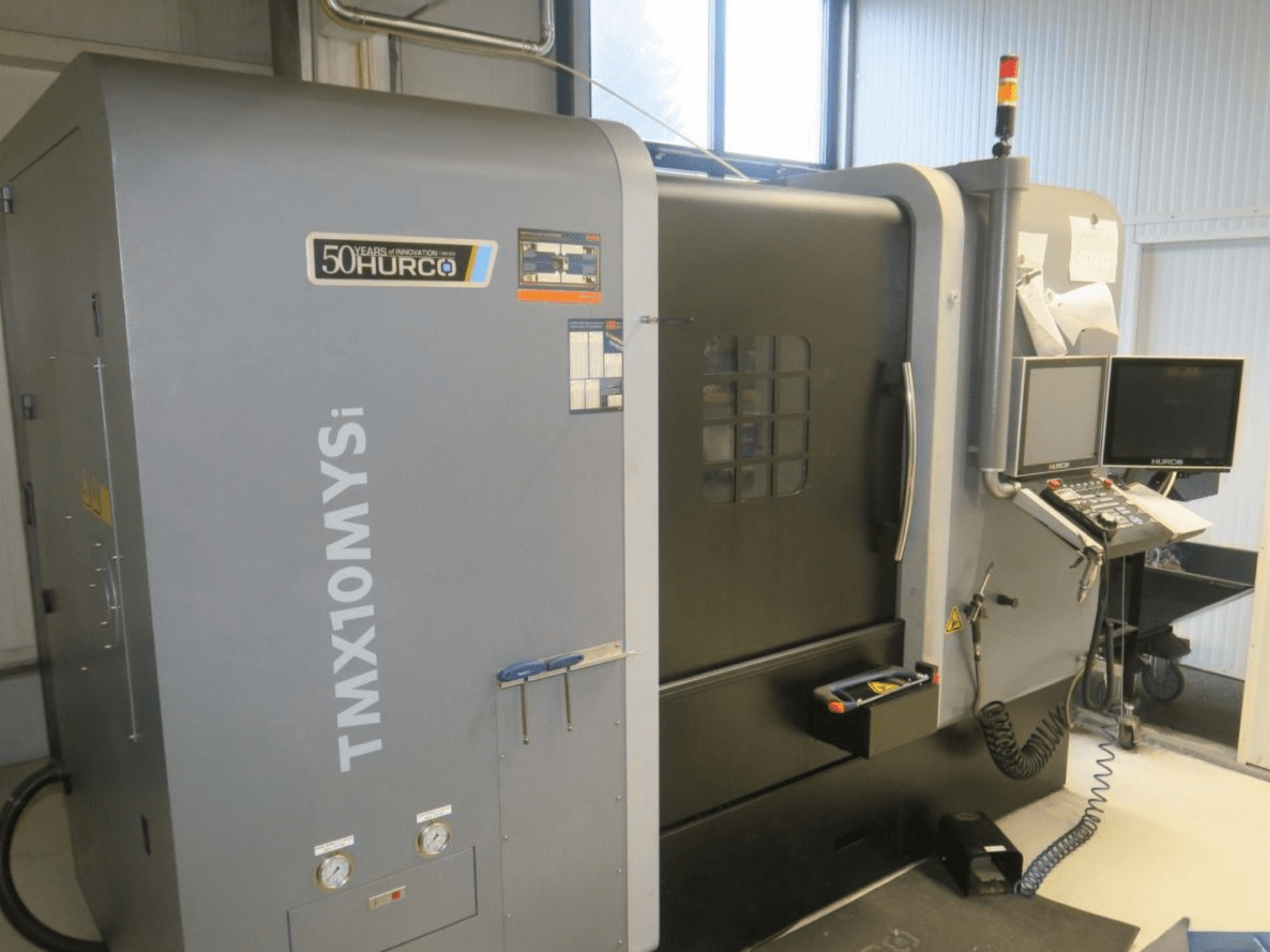 Bočni pogled na CNC stroj Hurco TMX10MYSi; prikazuje upravljačku ploču, svjetla za nuždu i mjerače.