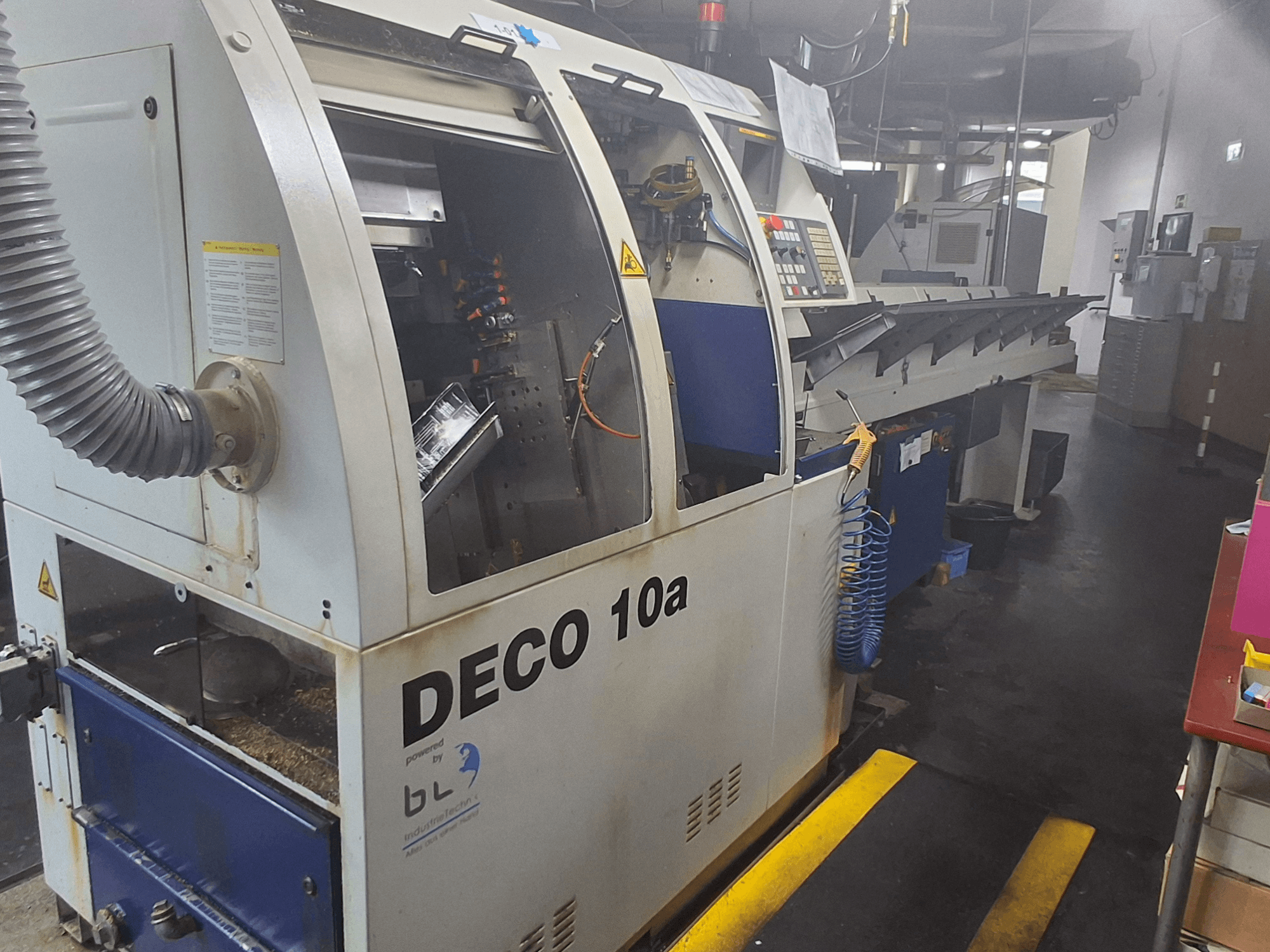 Švicarski tokarski stroj TORNOS DECO 10a, prednji pogled; ima upravljačku ploču, vidljive mehanizme i cijev za usisavanje prašine.