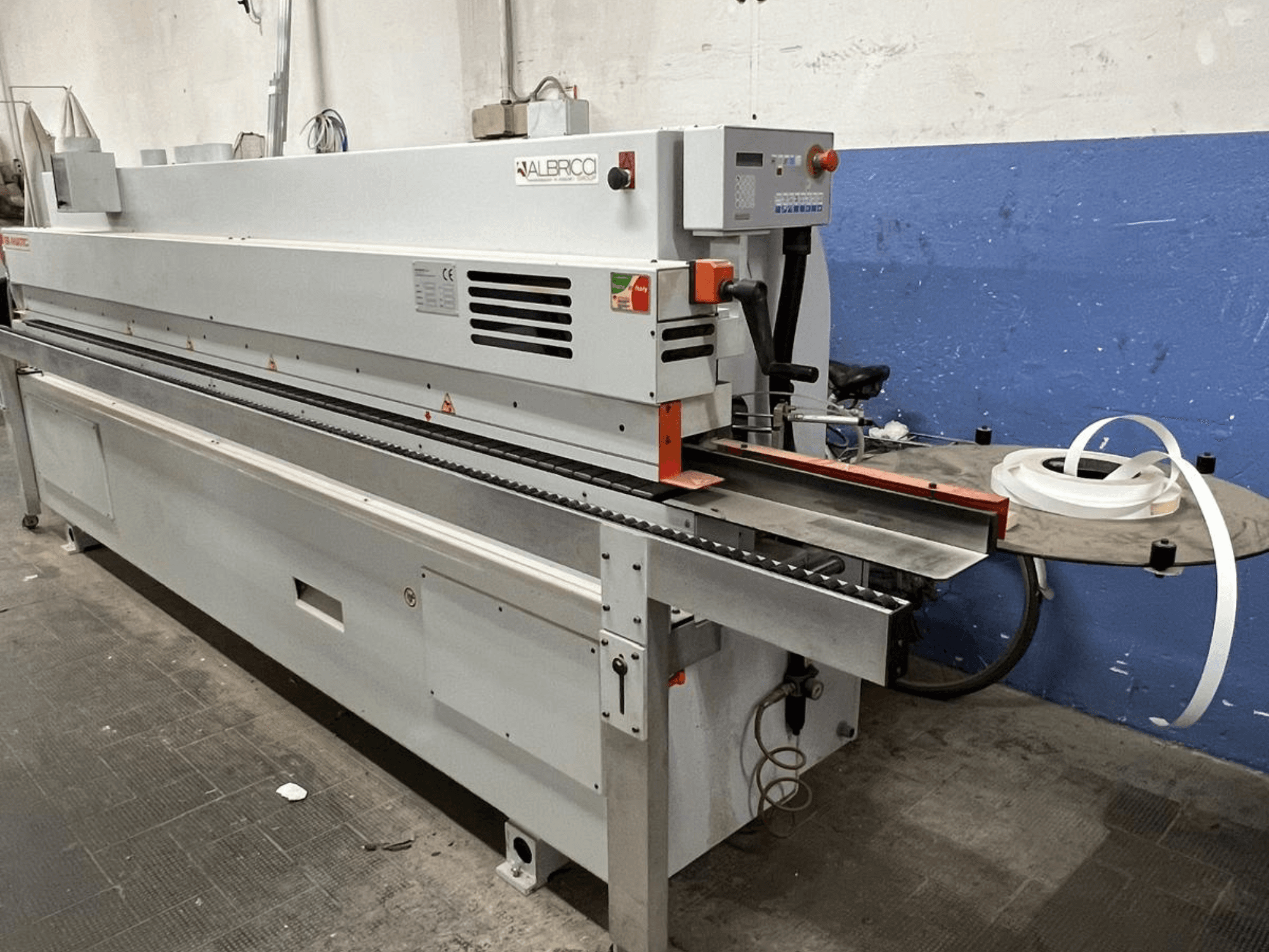 ALBRICO stroj za lijepljenje rubova s prednjim pogledom, s dugom transportnom trakom i pričvršćenom rolom ljepljive trake.