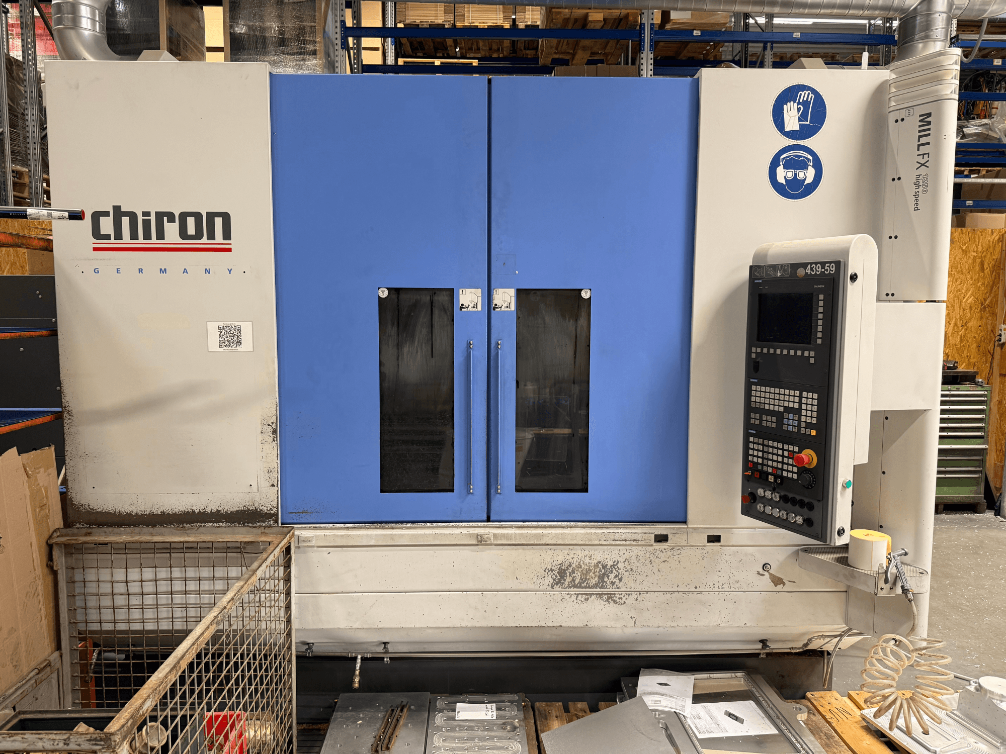 Vertikalni obradni centar CHIRON MILL FX 1250, prednji pogled, s upravljačkom pločom i sigurnosnim simbolima, spreman za precizan rad.