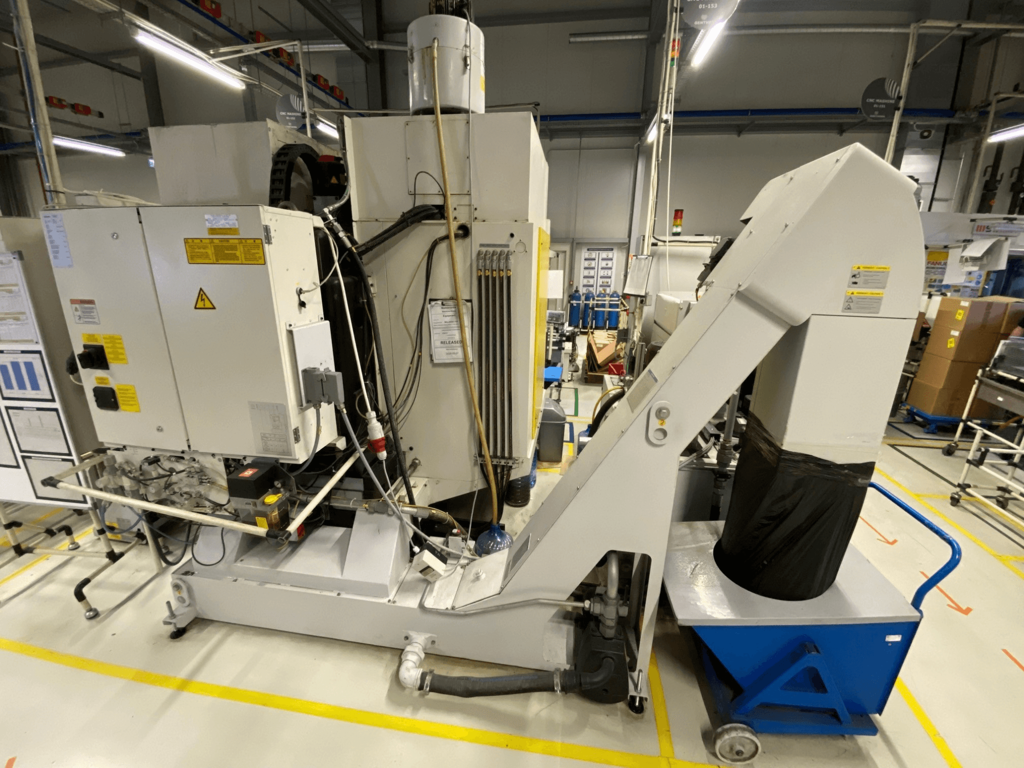 Prednji pogled na vertikalni obradni centar FANUC ROBODRILL α-D21LiB, s prikazom električnih komponenti i izlaznog kanala.