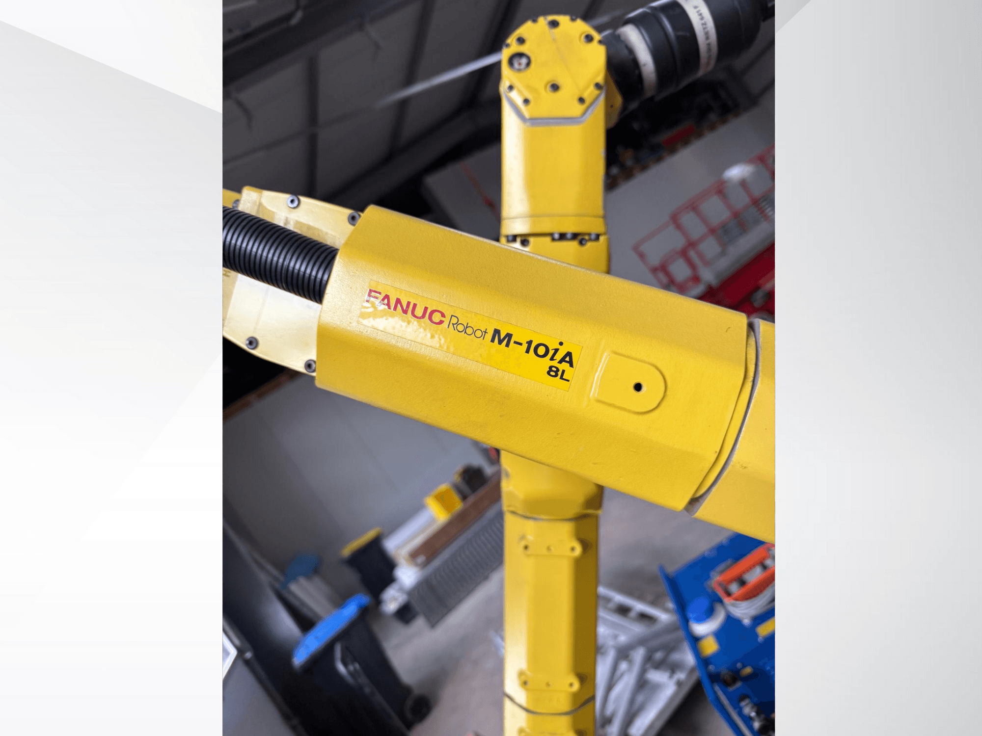 FANUC robot M-10iA 8L u žutoj boji, gledan sa strane, prikazuje zglob ruke i mehaničke komponente u industrijskom okruženju.