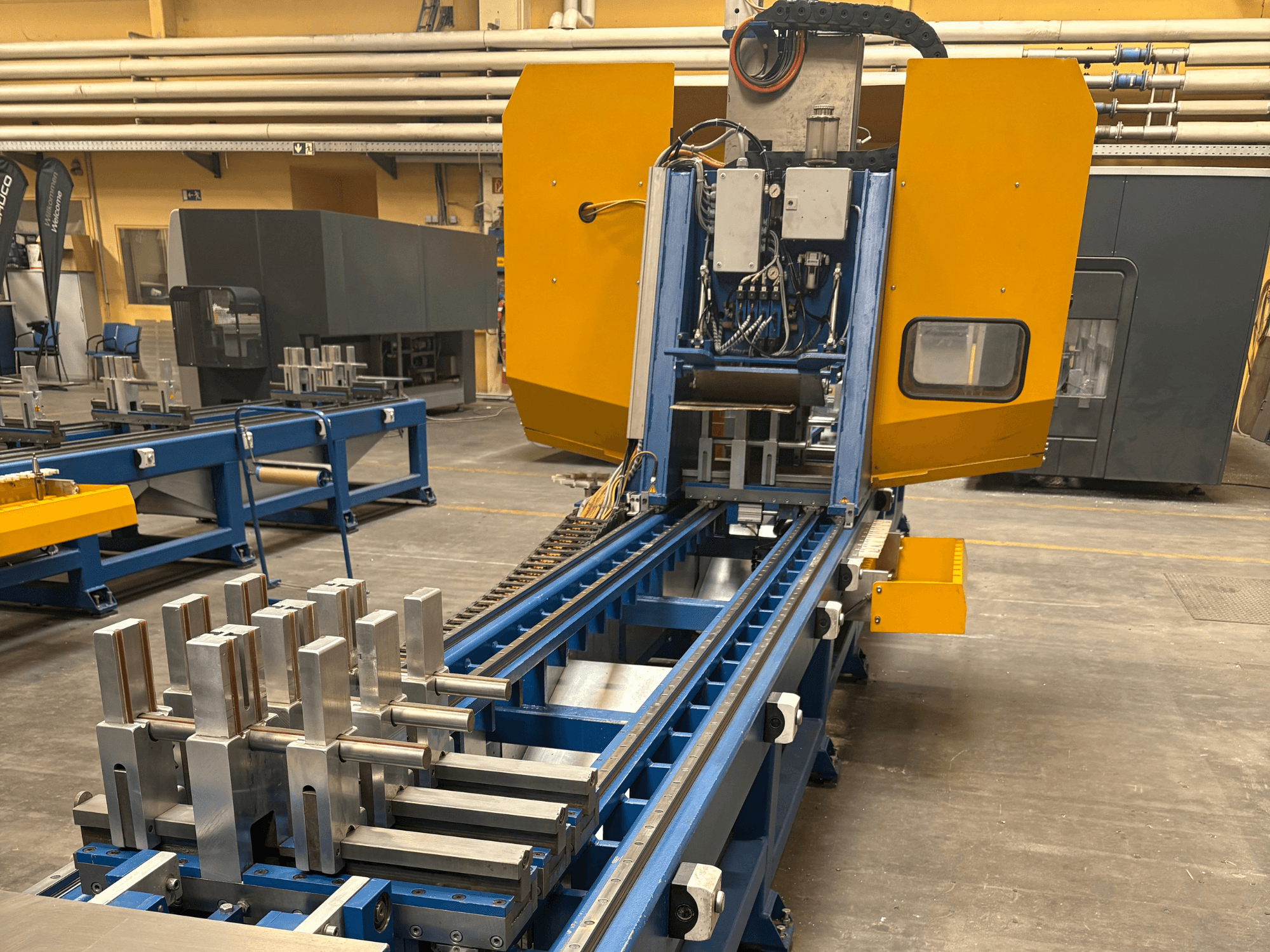 Prednji pogled na univerzalni obradni centar SCHÜCO PBX AL, s metalnim obratcima na plavoj obradnoj površini.