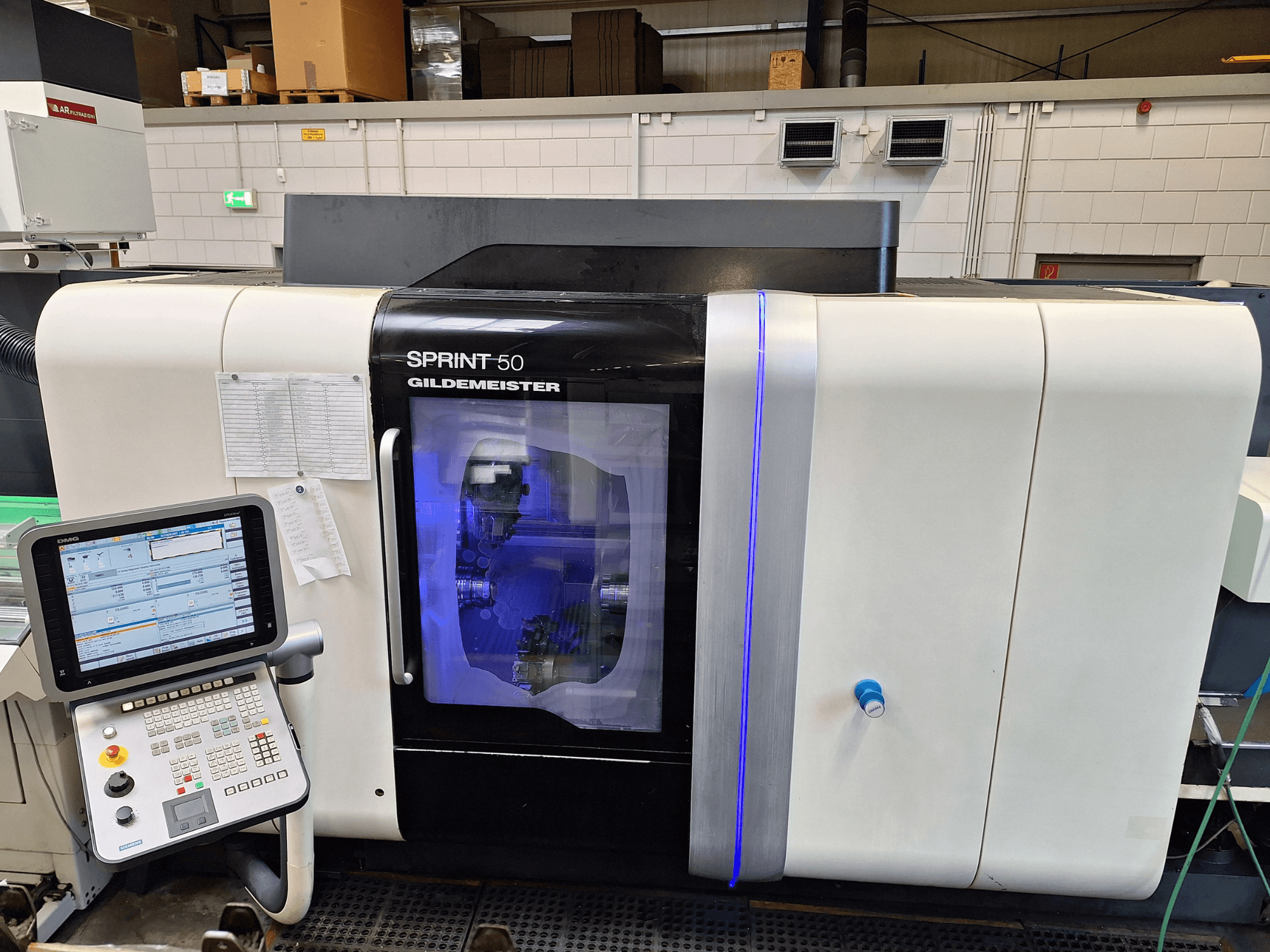 DMG Sprint 50 2T horizontalni tokarski stroj, prednji pogled, s upravljačkom pločom i prozirnim kućištem koje prikazuje strojeve unutra.