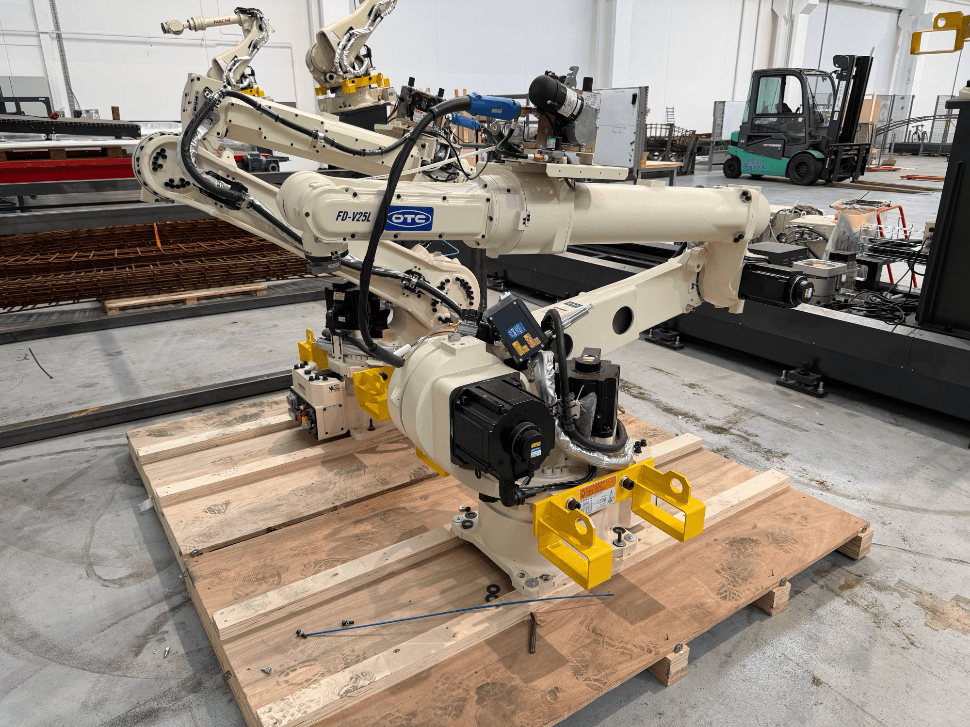 Robotska ruka Daihen FD19-V25L, dostupna bez recepta, u prednjem pogledu, sa žutim hvataljkama i vidljivim mehaničkim komponentama na drvenoj paleti.