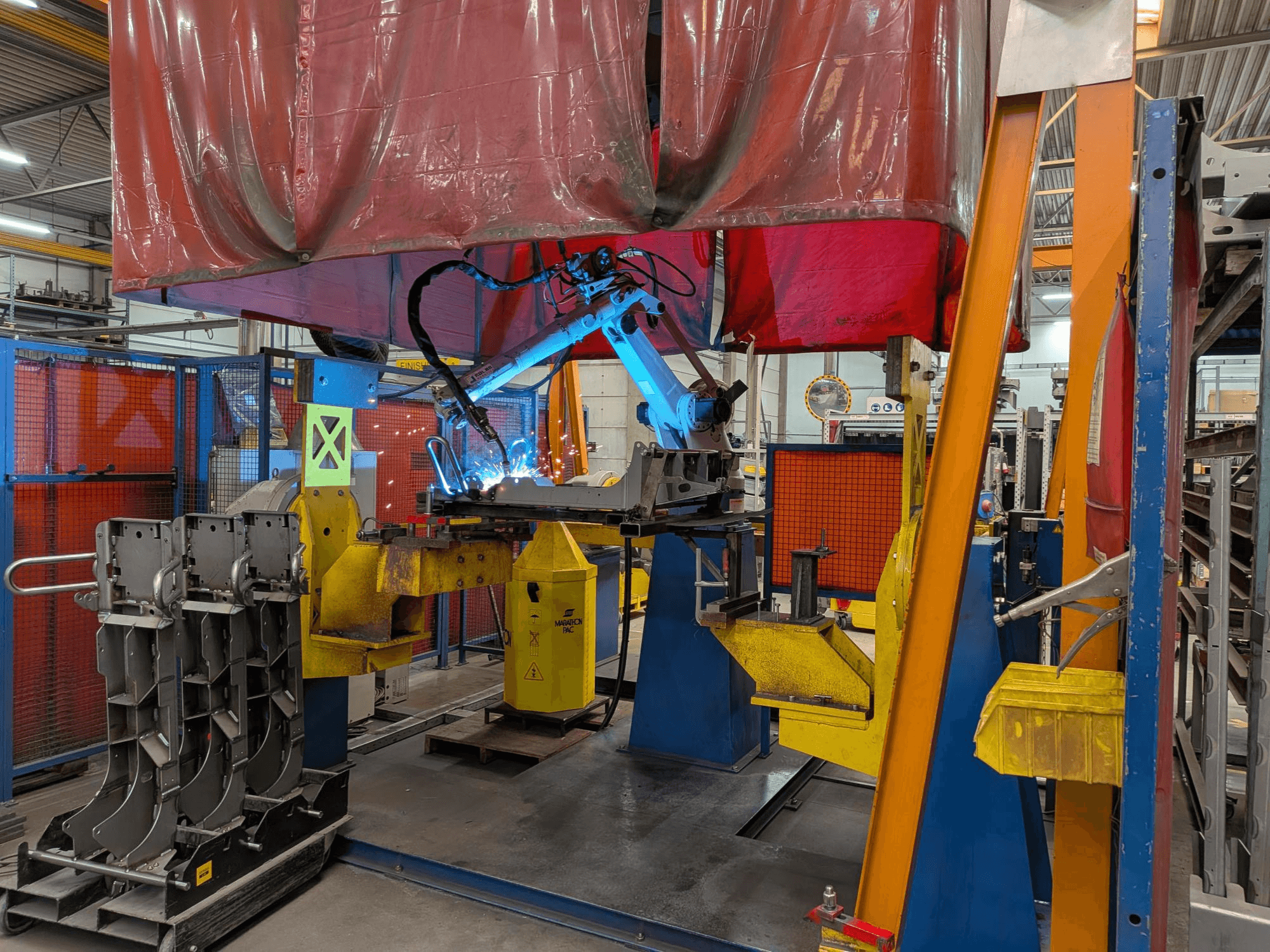 Robot za zavarivanje OTC Daihen DR4200 u akciji, gledano sprijeda, s jarkoplavim lukom za zavarivanje i zaštitnim poklopcem.