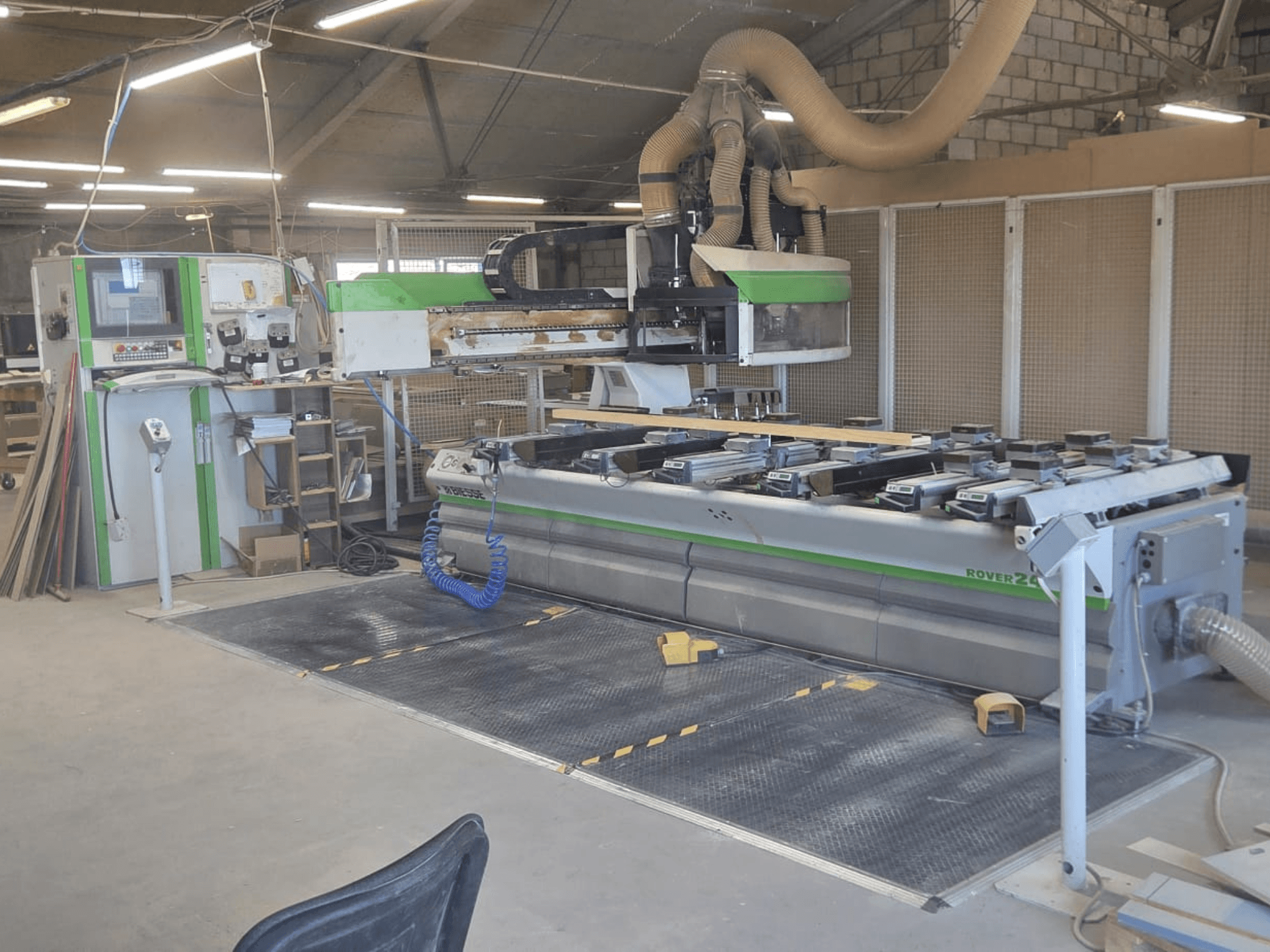 CNC obradni centar BIESSE Rover 24S u radionici, s upravljačkom pločom i velikom radnom površinom s drvenim komadima.