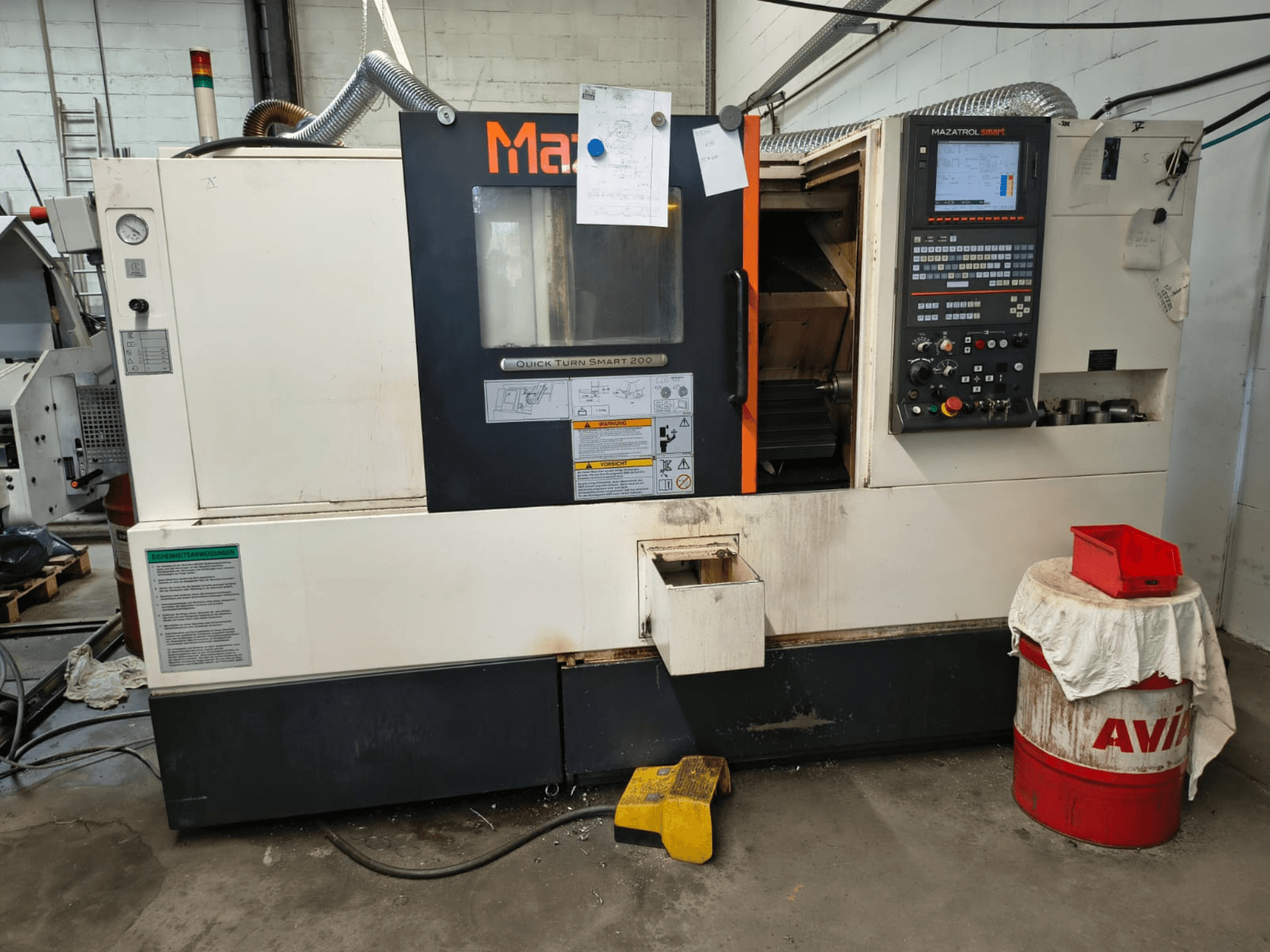 Mazak Quick Turn Smart 200, horizontalni tokarski stroj, prednji pogled s vidljivom upravljačkom pločom, spremnikom rashladne tekućine i oznakama.