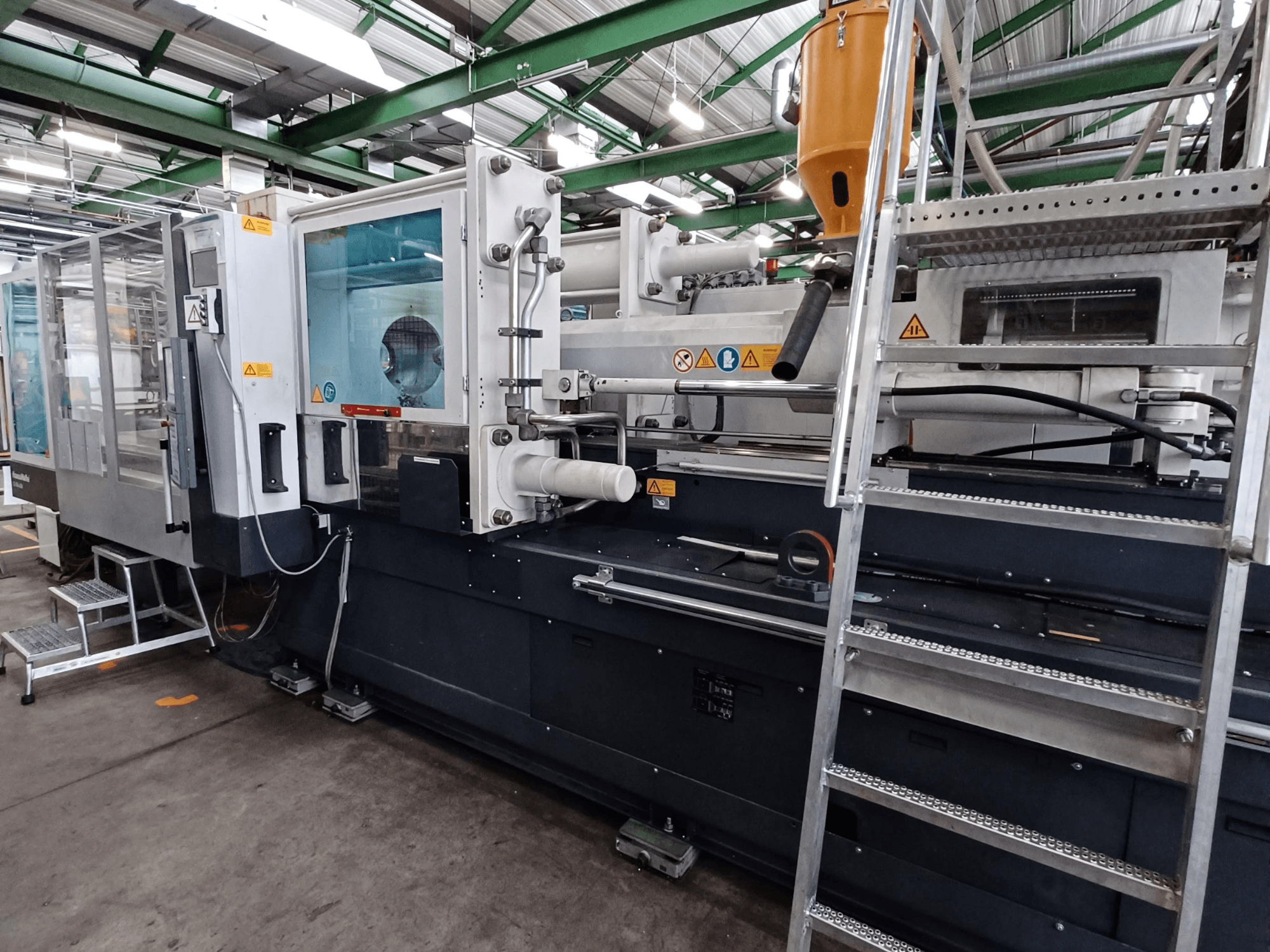 Industrijski stroj za brizganje plastike s jasnim prednjim pogledom, koji prikazuje oznake robne marke, upravljačku ploču i spremnik materijala.