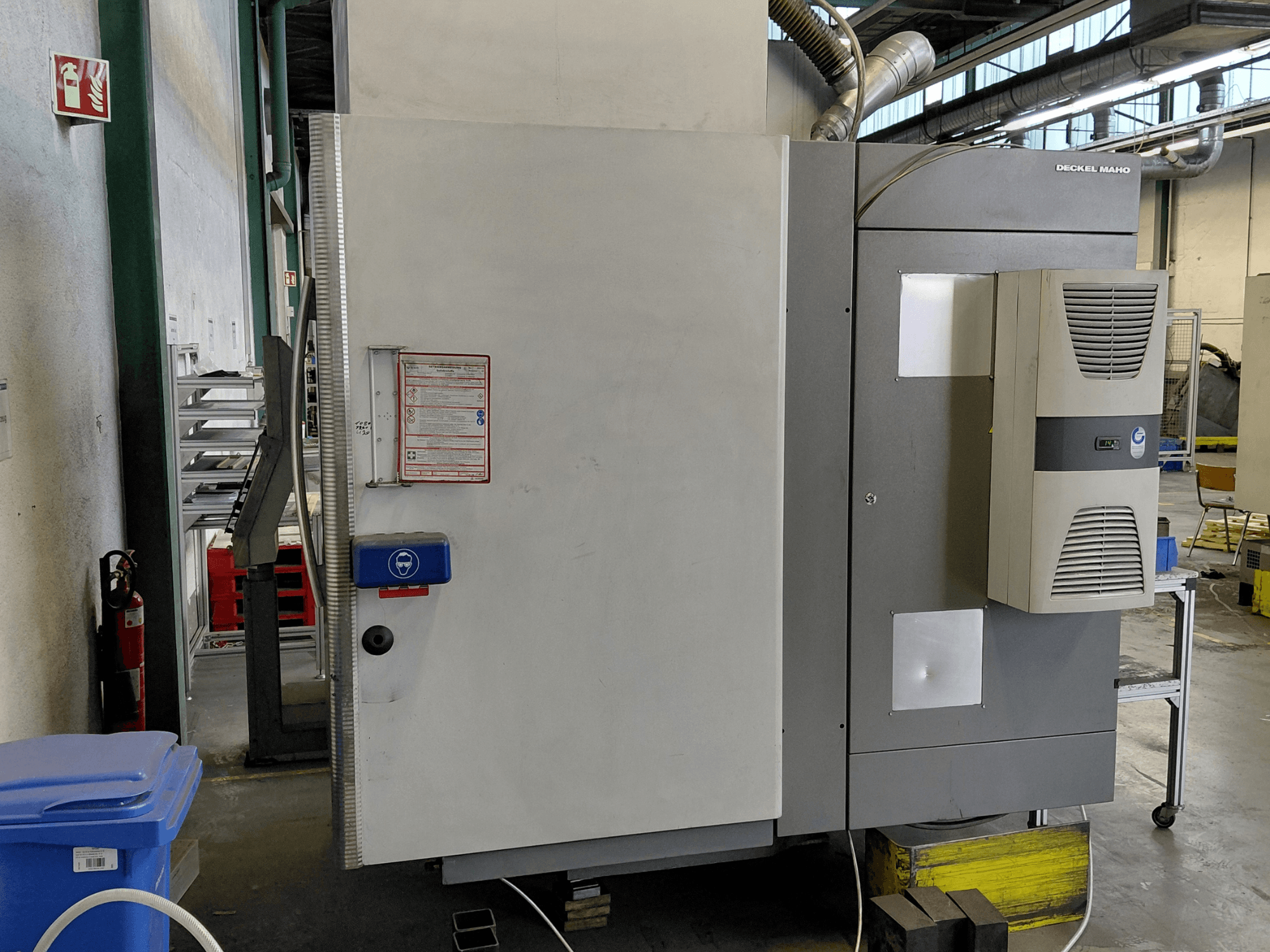 Bočni pogled na vertikalni obradni centar DECKEL MAHO DMC 635 V s vidljivom upravljačkom pločom i sigurnosnim naljepnicama.