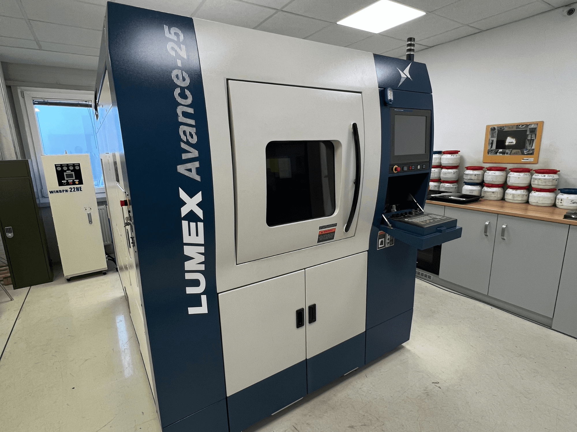 3D printer LUMEX Avance-25 u laboratorijskom okruženju, prednji pogled. Upravljačka ploča s vidljivim zaslonom i gumbima, oprema u pozadini.