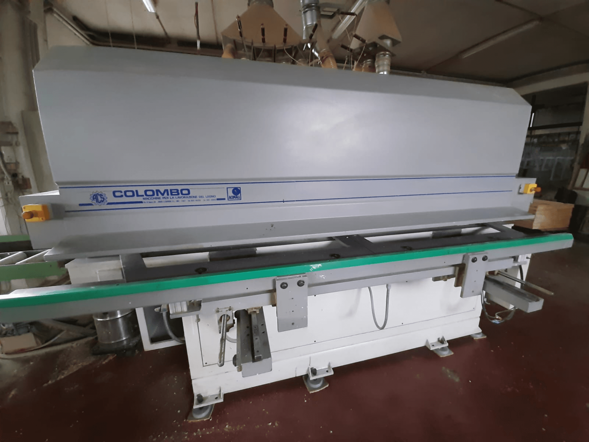 Stroj za obradu drva u Colombu, prednji pogled, s dugim zelenim stolom, upravljačkim tipkama i sivim kućištem s plavim detaljima.