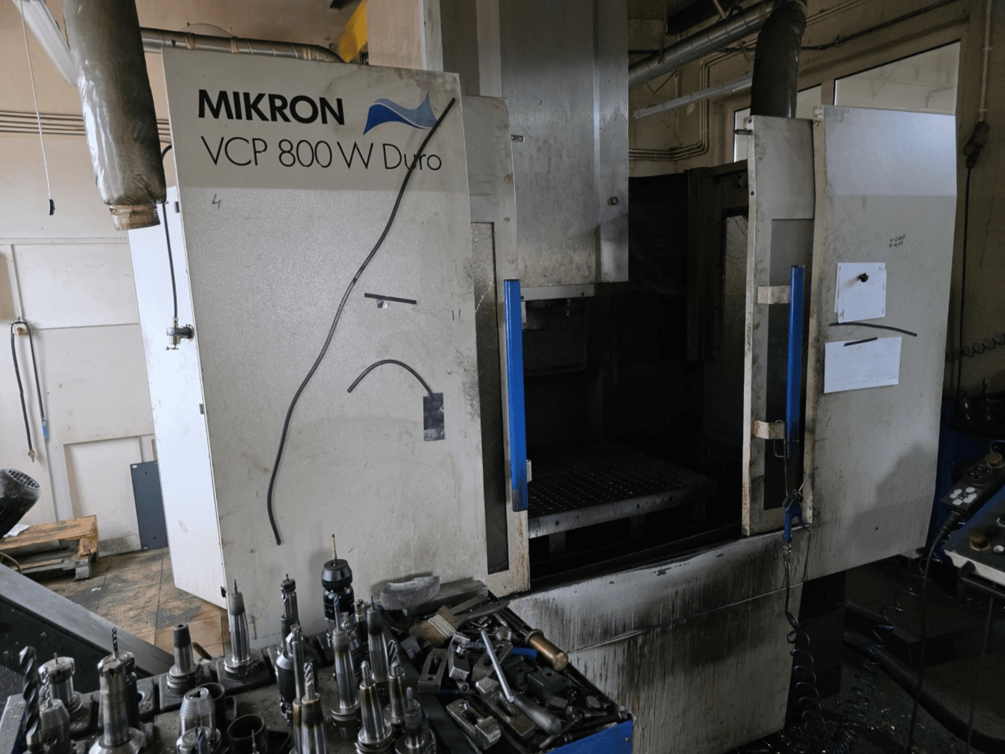 Glodalica Mikron VCP 800 W Duro prikazana je s bočnog gledišta, s alatima i kontrolama vidljivim u prvom planu.