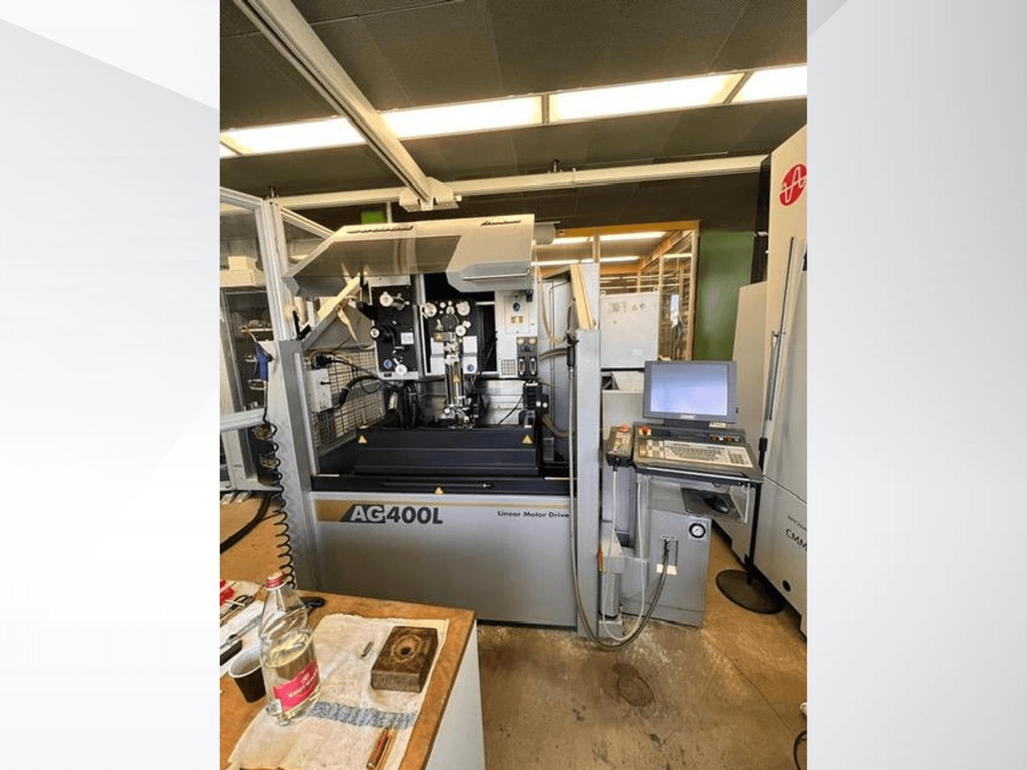 Linearni motorni pogonski stroj AG400L, prednji pogled, s upravljačkom pločom i radnim prostorom s vidljivim sigurnosnim značajkama.