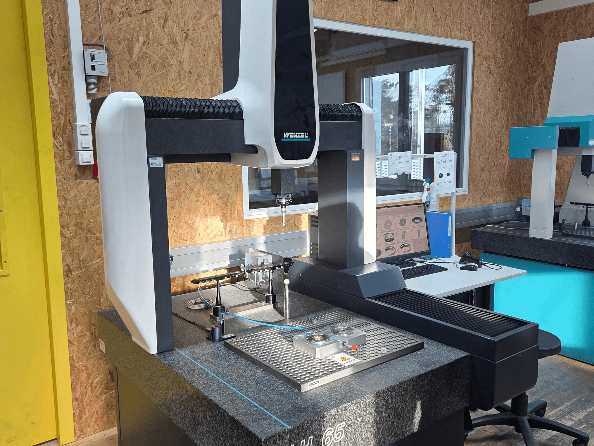 Koordinatni mjerni stroj Wenzel LH 65 u laboratorijskoj postavci, prednji pogled, s prikazom mjernih alata i monitora.