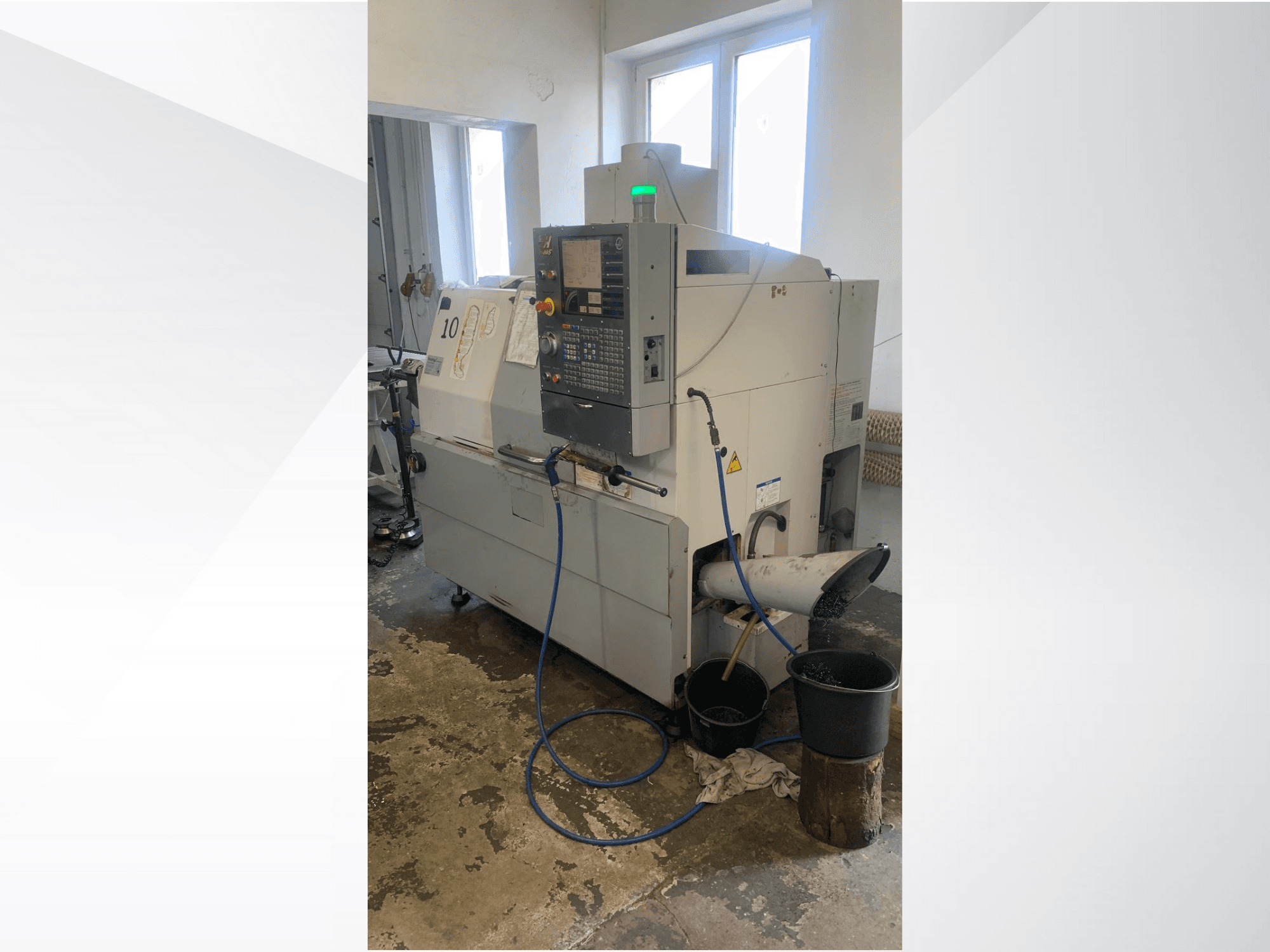 Model Haas CNC stroja s upravljačkom pločom, bočni pogled, s cijevi za rashladnu tekućinu, žlijebom za otpad i spremnicima za pohranu ispod.