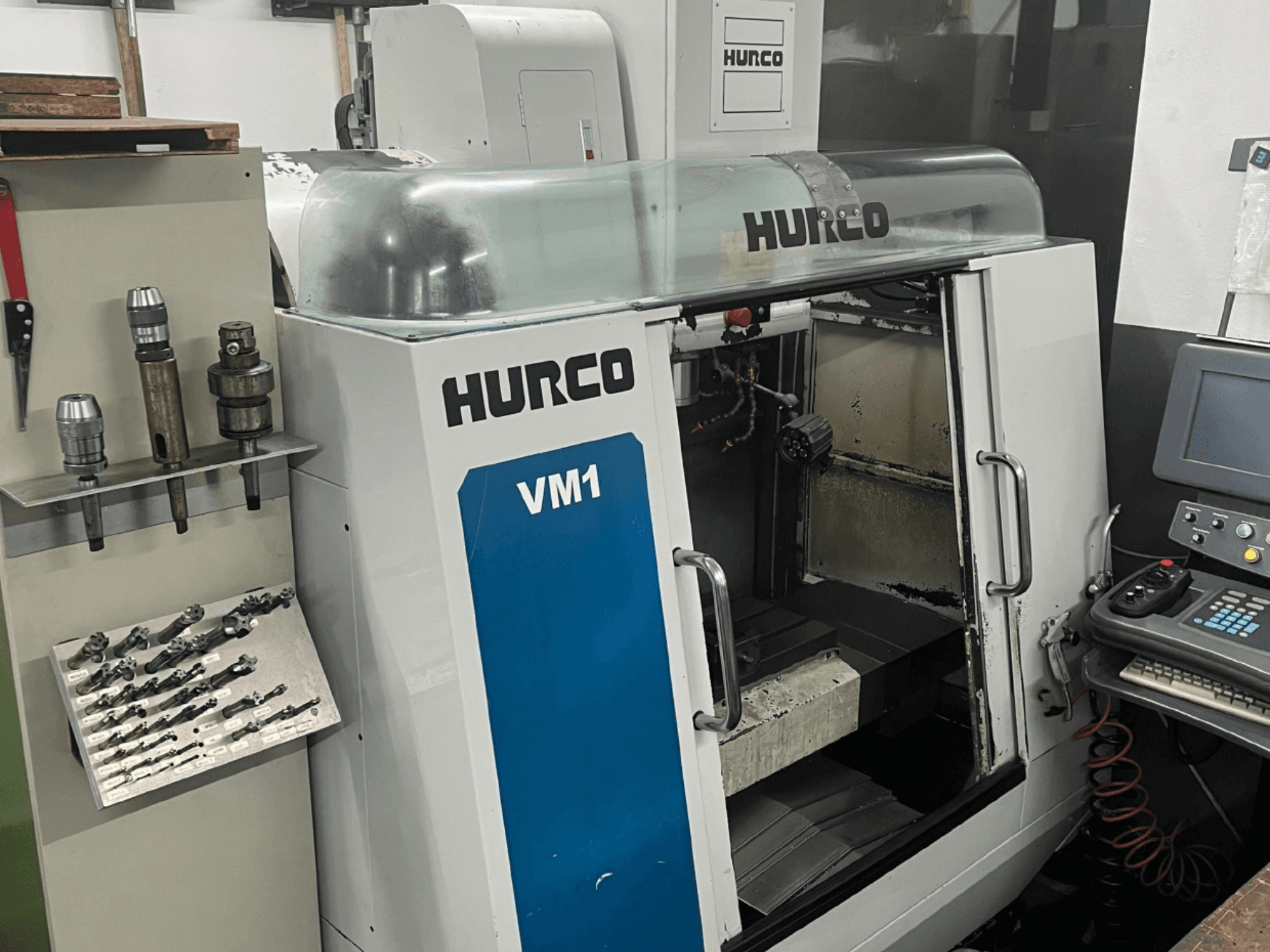 Prednji pogled na vertikalni obradni centar Hurco VM1, s prozirnim poklopcem, upravljačkom pločom i montiranim alatima.