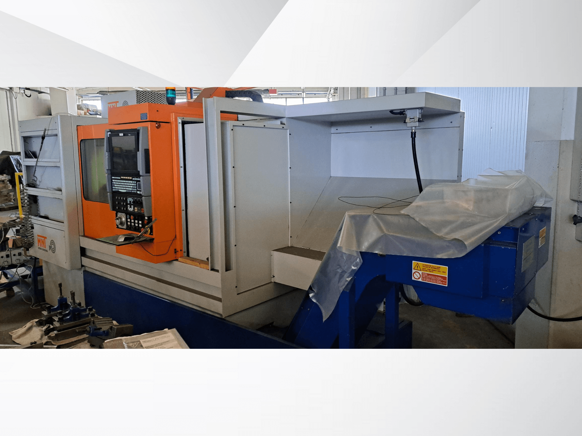 MNT CNC stroj, prednji pogled, s narančastom upravljačkom pločom, velikim područjem za obradu i jedinicom za odlaganje otpadnih materijala.