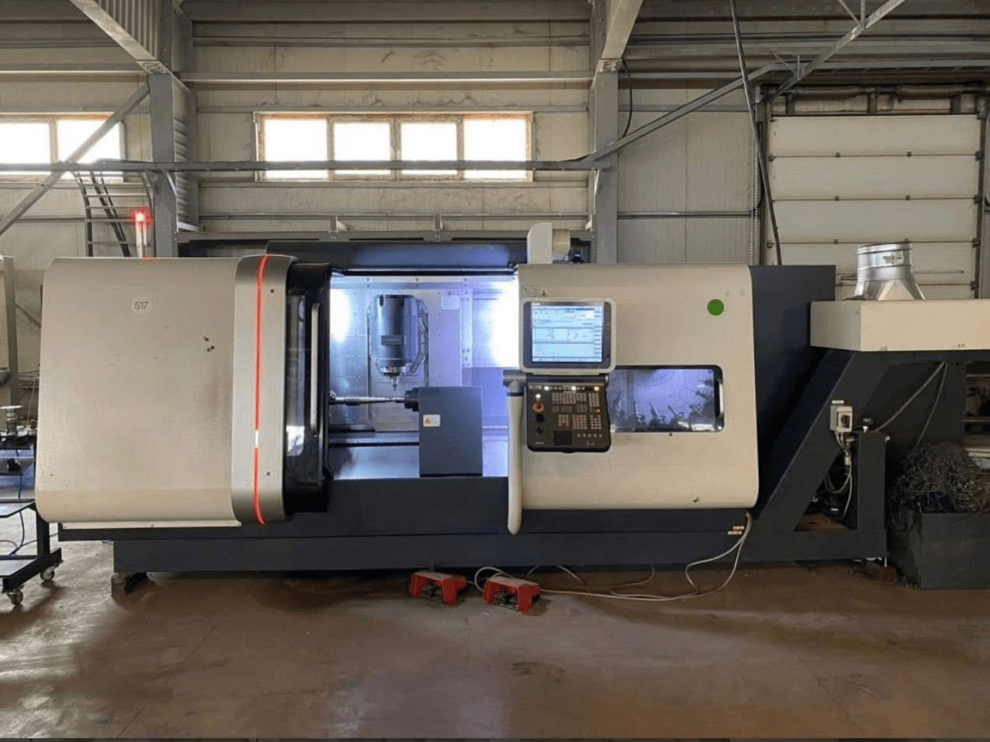 DMG MORI Beta 1250 TC tokarsko-glodački centar, prednji pogled s upravljačkom pločom, osvijetljenim radnim prostorom i vidljivim alatima za rezanje.