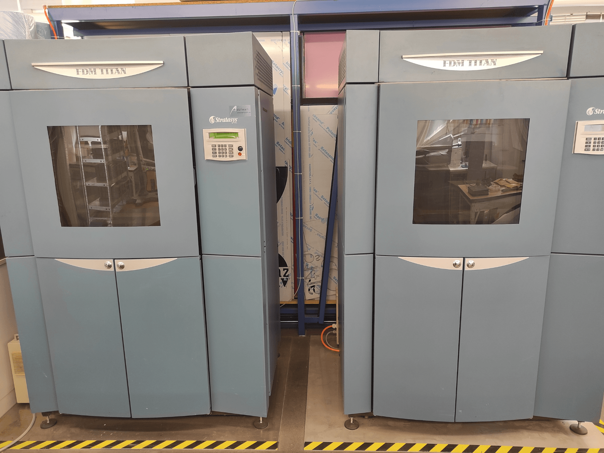 FDM TitanTI 3D printer tvrtke Stratasys, prednji pogled, s dvostrukim vratima i upravljačkom pločom, smješten u industrijskom okruženju.