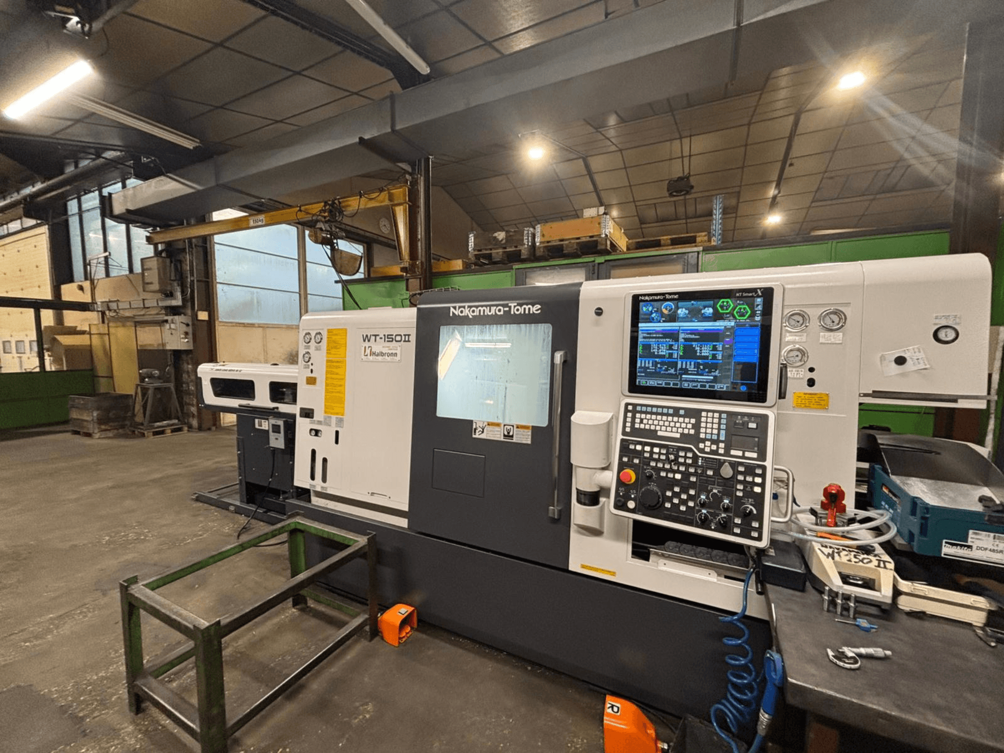 Stroj Nakamura-Tome WT-150II, pogled sprijeda, s upravljačkom pločom i alatima vidljivim na radnom stolu u radioničkom okruženju.