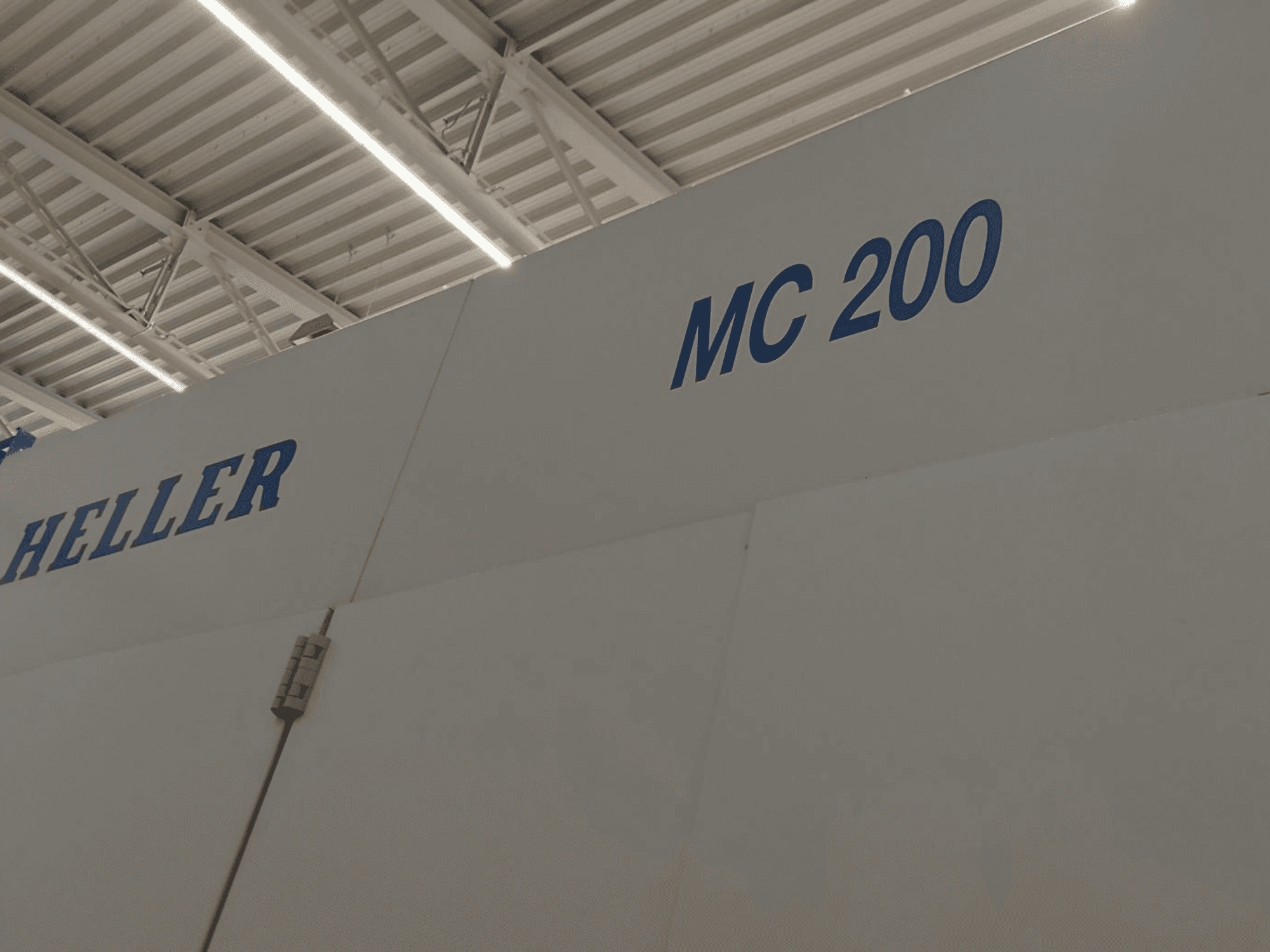 Horizontalni obradni centar Heller MC 200, prikazan sa strane, s istaknutim markom i modelom plavim slovima na bijeloj površini.