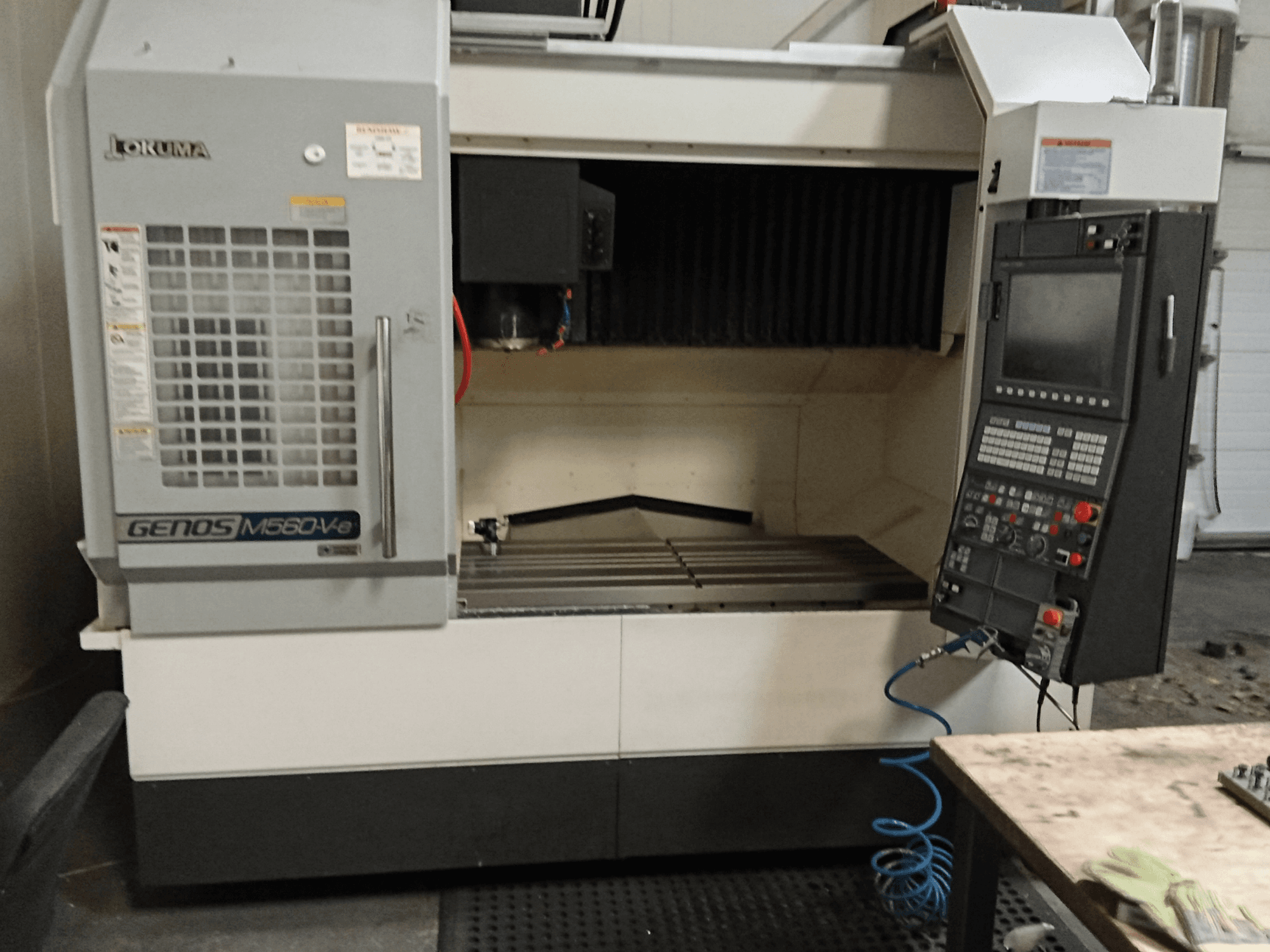 Okuma GENOS M560-V, prednji pogled na vertikalni obradni centar s upravljačkom pločom, CNC sučeljem i vidljivim područjem rezanja.